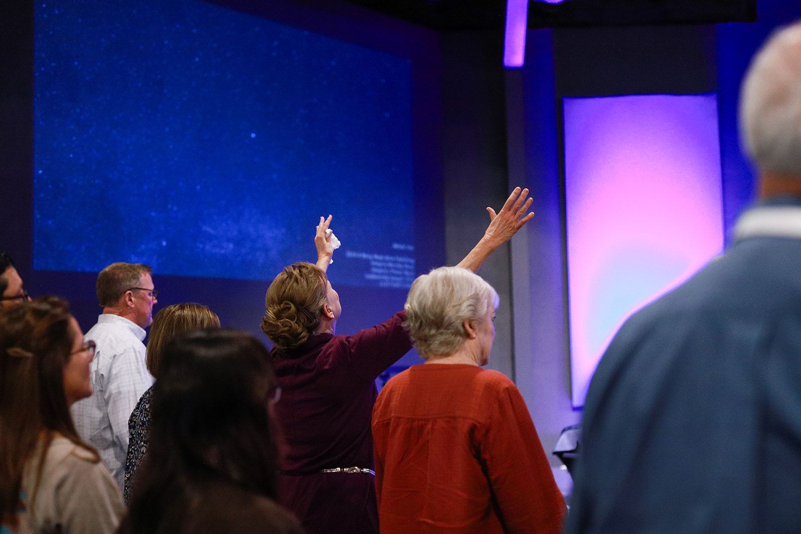 A group of people are sitting at tables in a kitchen eating food.
