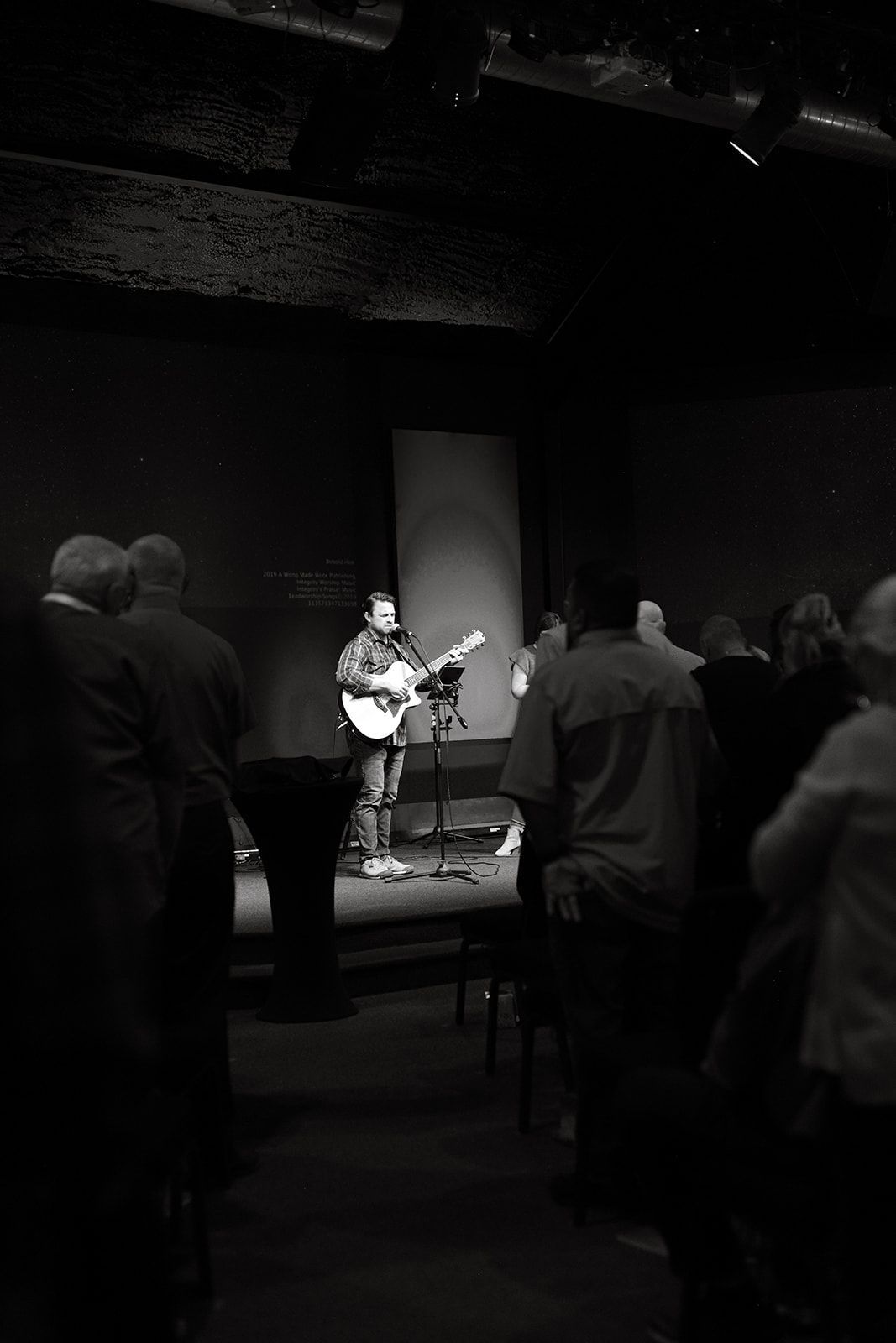 A black and white photo of a wall with a sign that says we gather together