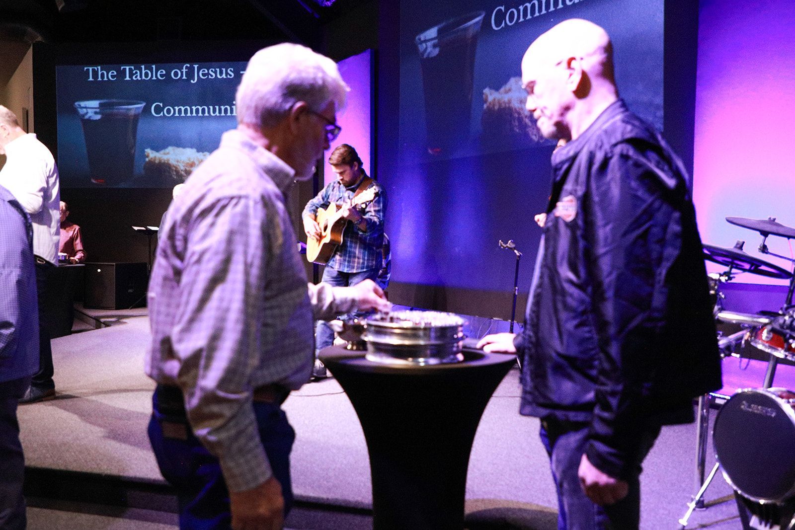 A man in a cowboy hat is talking to two other men