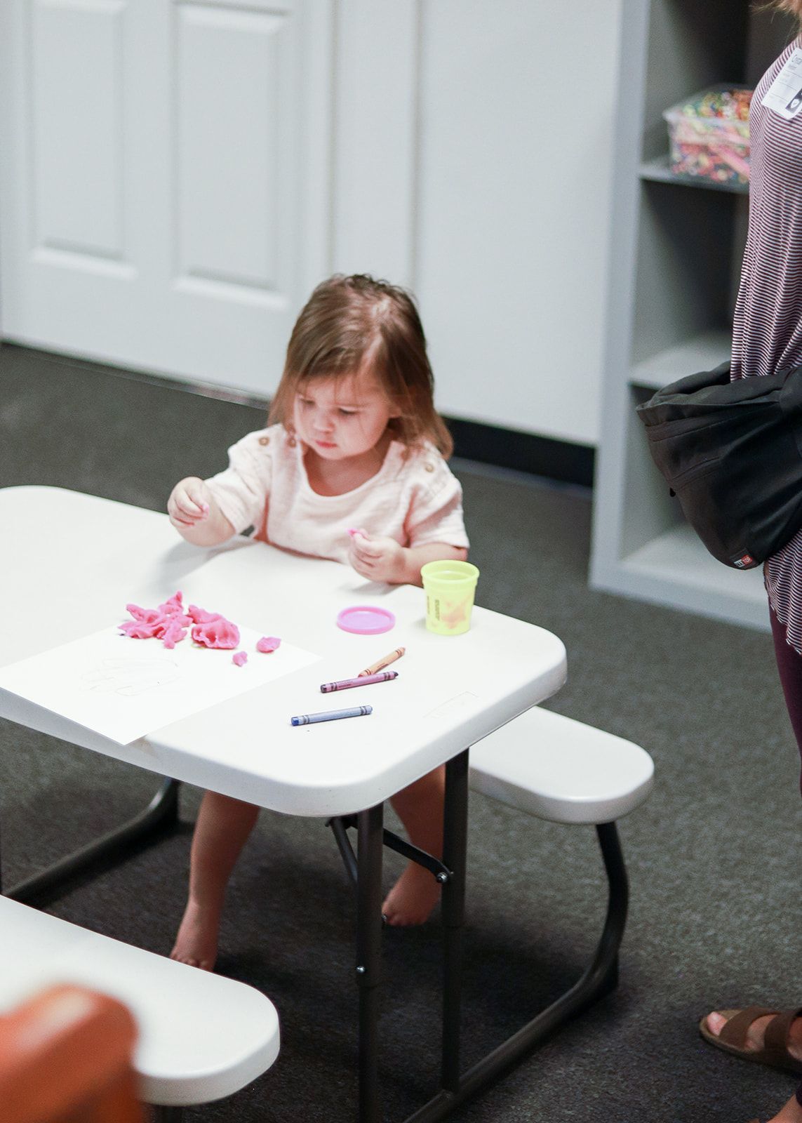 A little girl is sitting at a table playing with toys