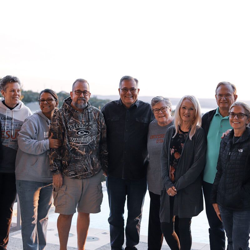 A group of people are posing for a picture in front of a body of water.