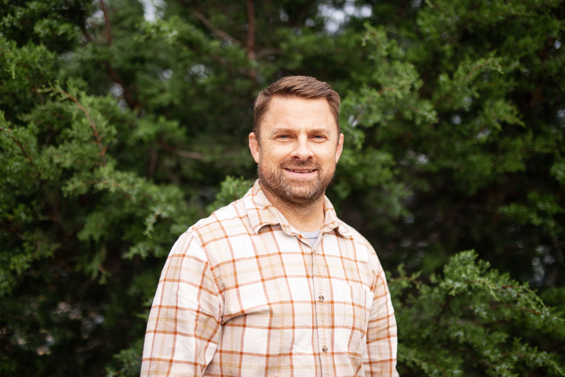 Man on a boat holding up a redfish, smiling. Sunny day, blue water.