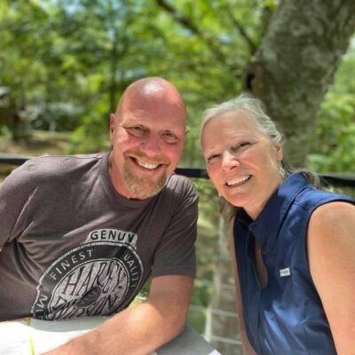 A man and a woman are posing for a picture and the man is wearing a shirt that says genuv