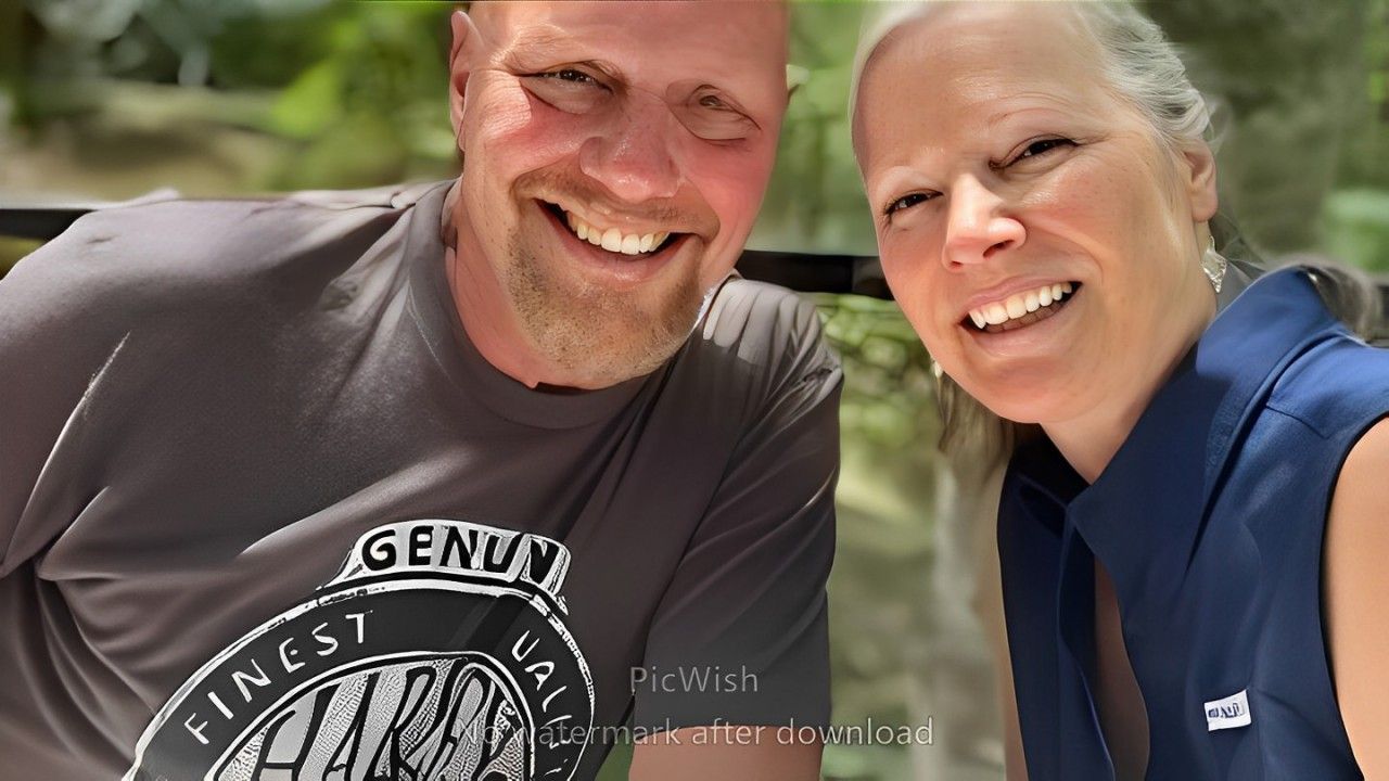 A man and a woman are posing for a picture and the man is wearing a genuine shirt