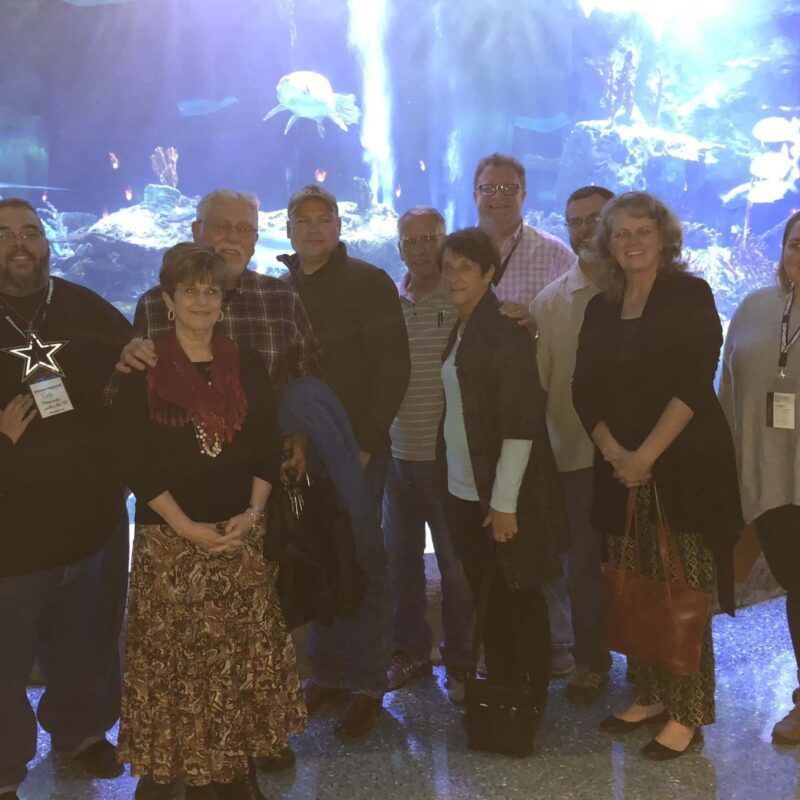 A group of people posing for a picture in front of an aquarium