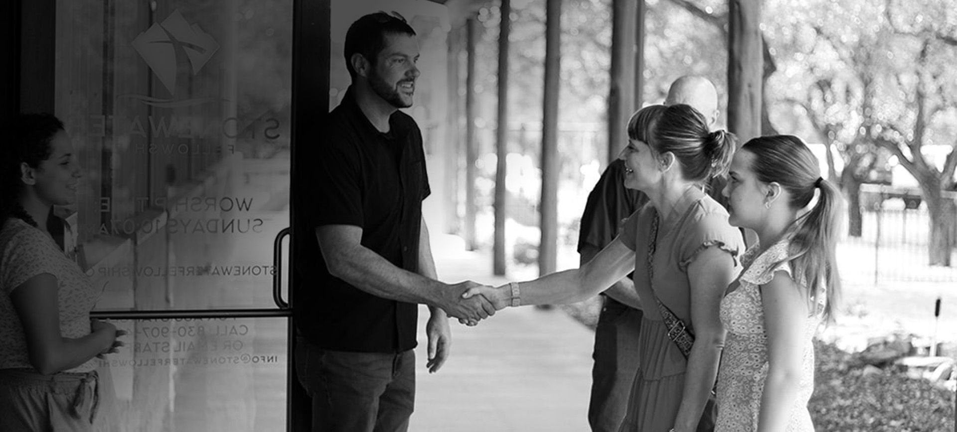 A group of people are shaking hands in a black and white photo.