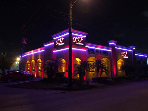 A restaurant is lit up with purple and red lights at night