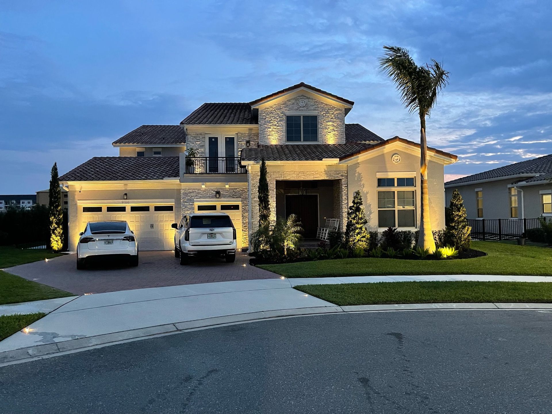 Two cars are parked in front of a large house.