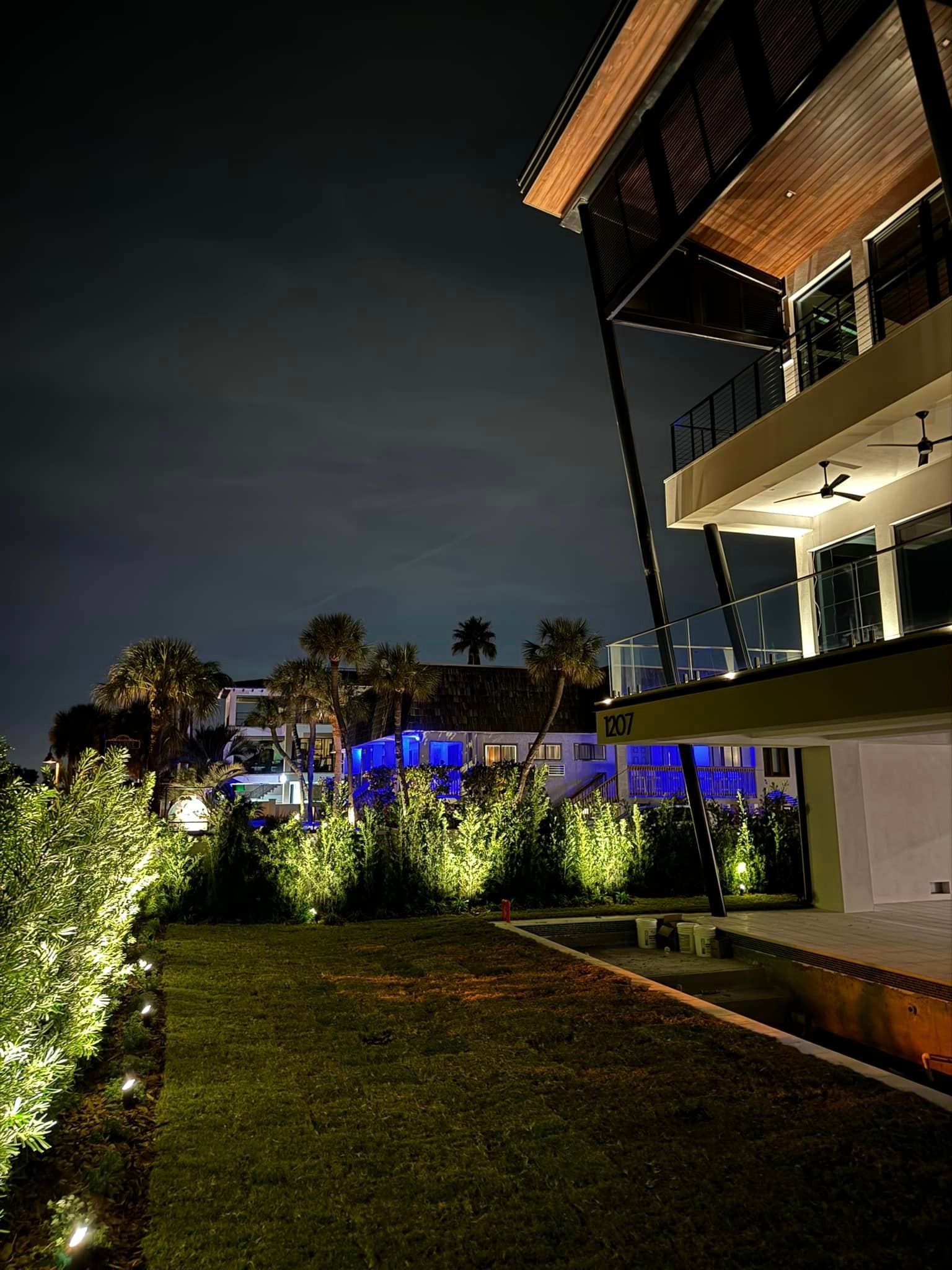 A large house is lit up by 80 bulbs at night with a swimming pool in the background.
