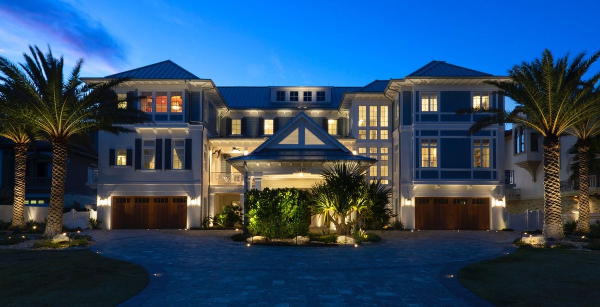 A large house with palm trees in front of it at night.