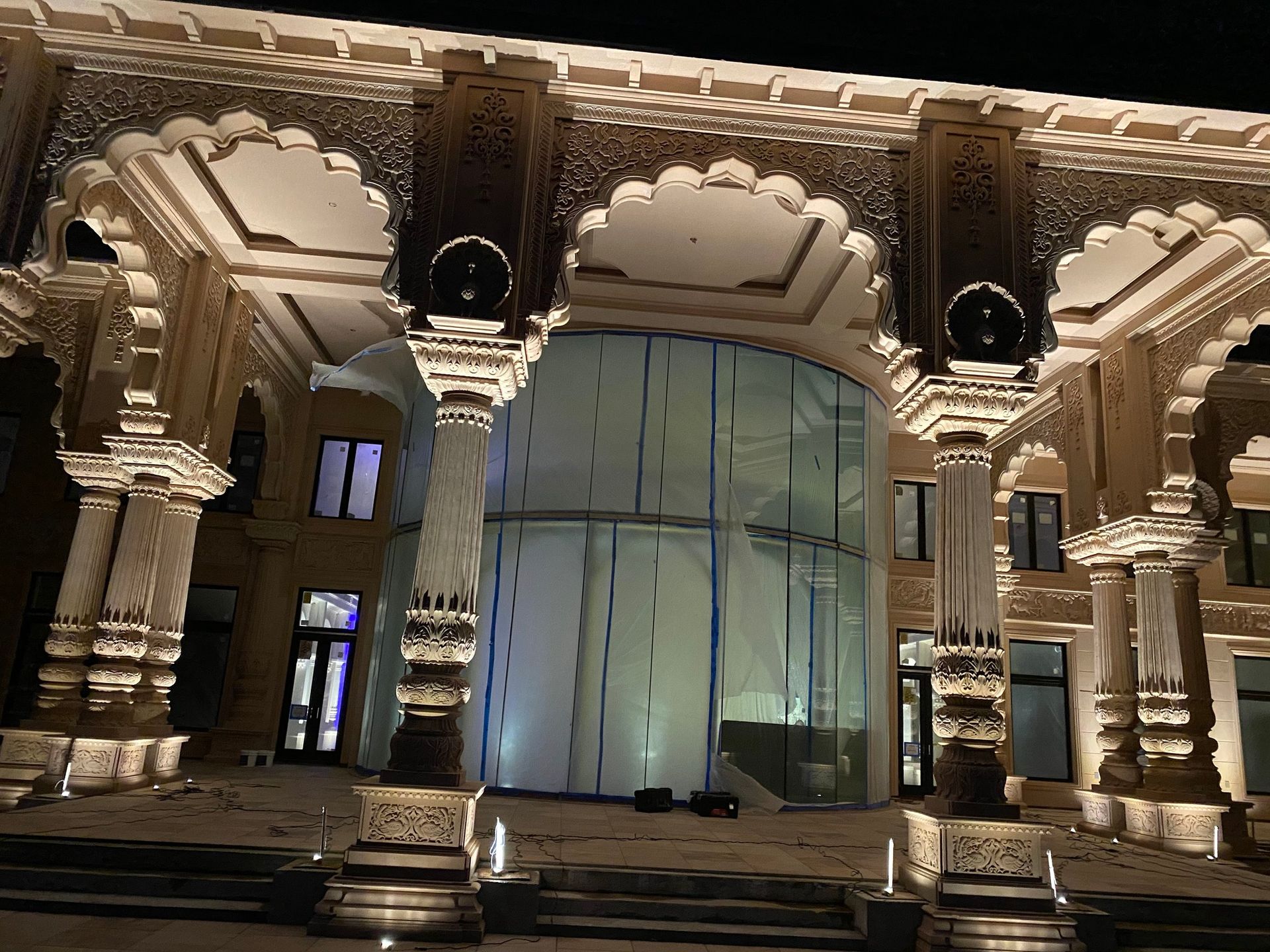 A large building with columns and stairs is lit up at night.