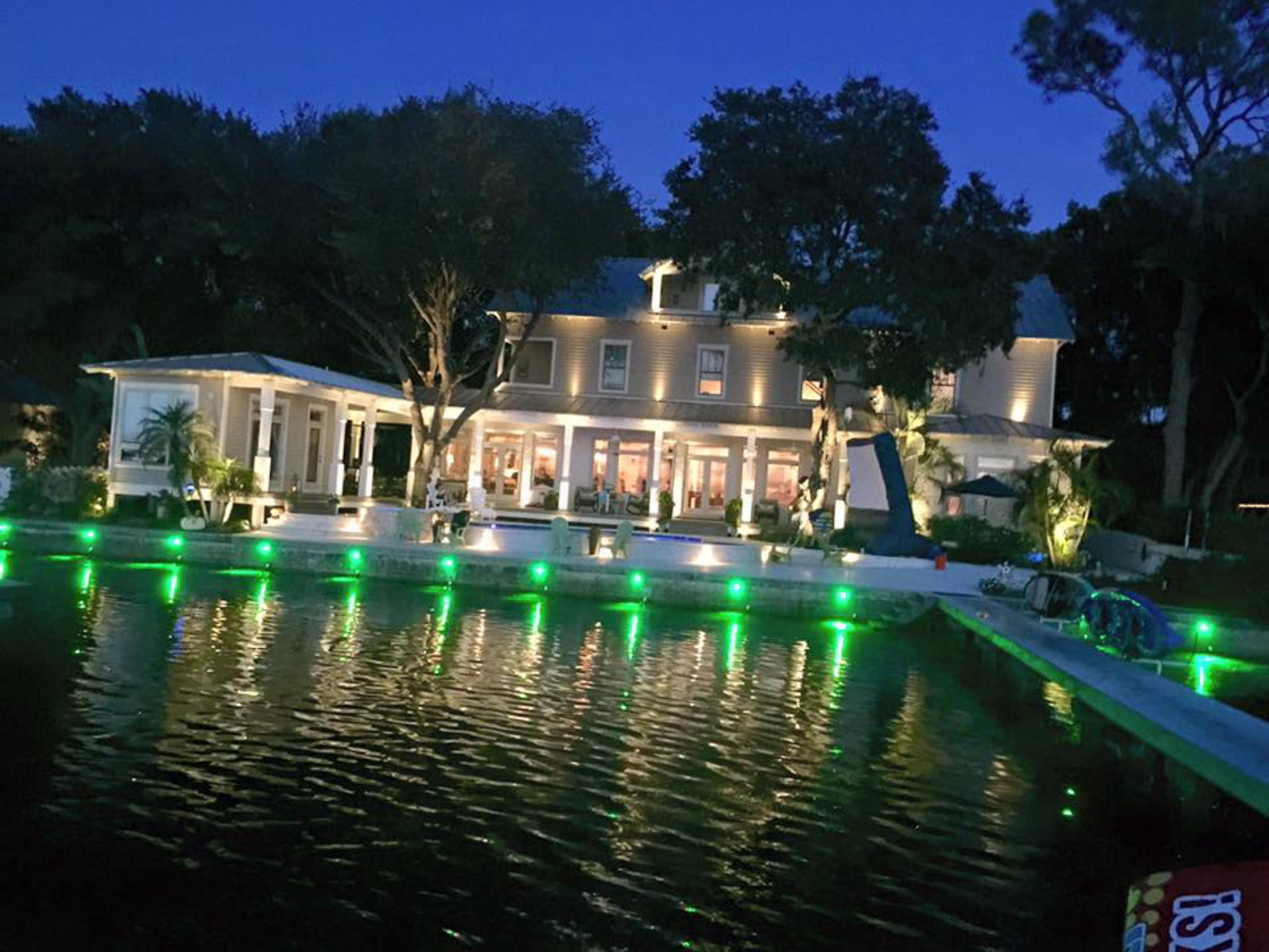 A large house is lit up at night with green lights