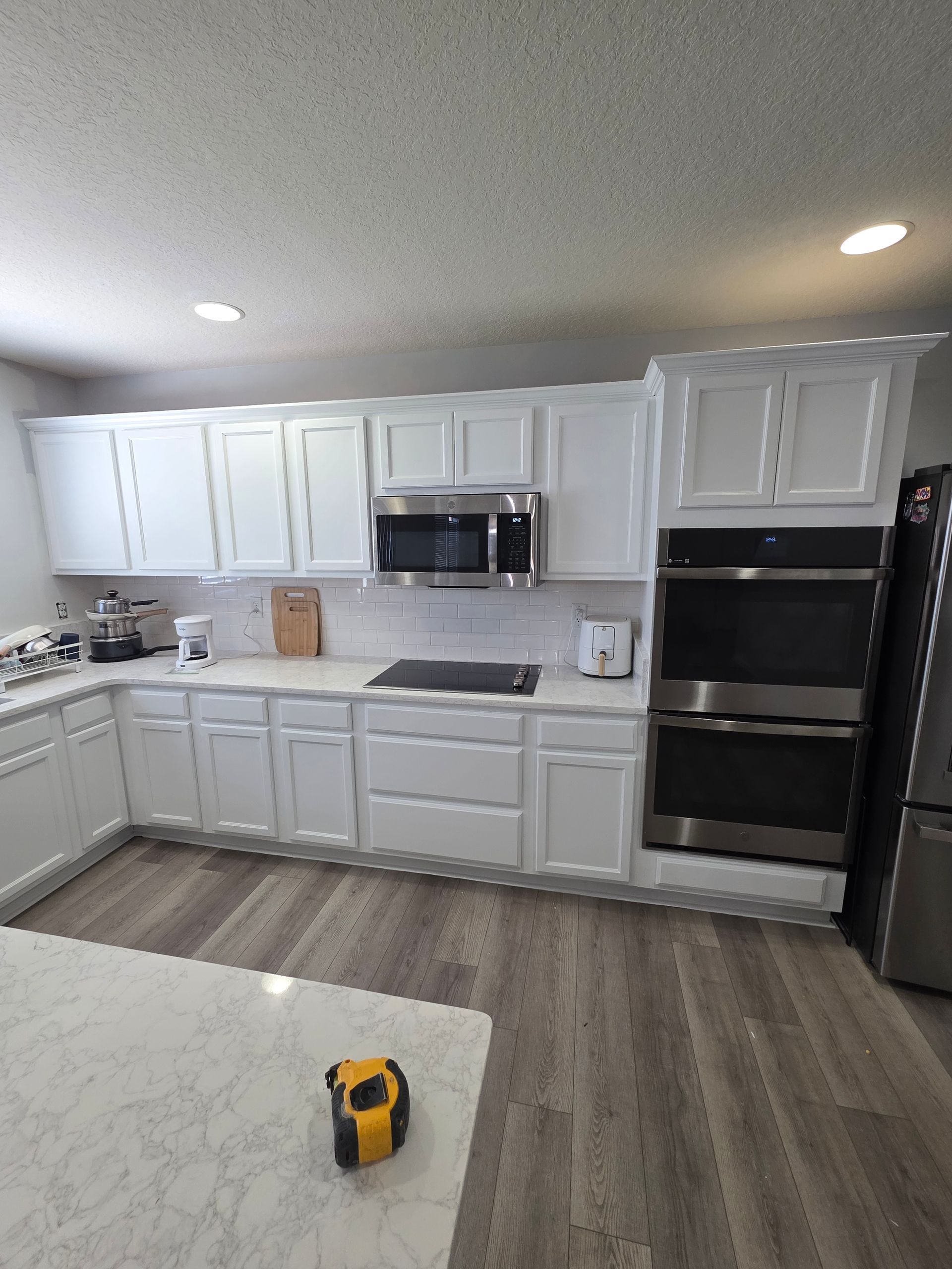 White kitchen with cabinets, appliances, and island. Hardwood floor.