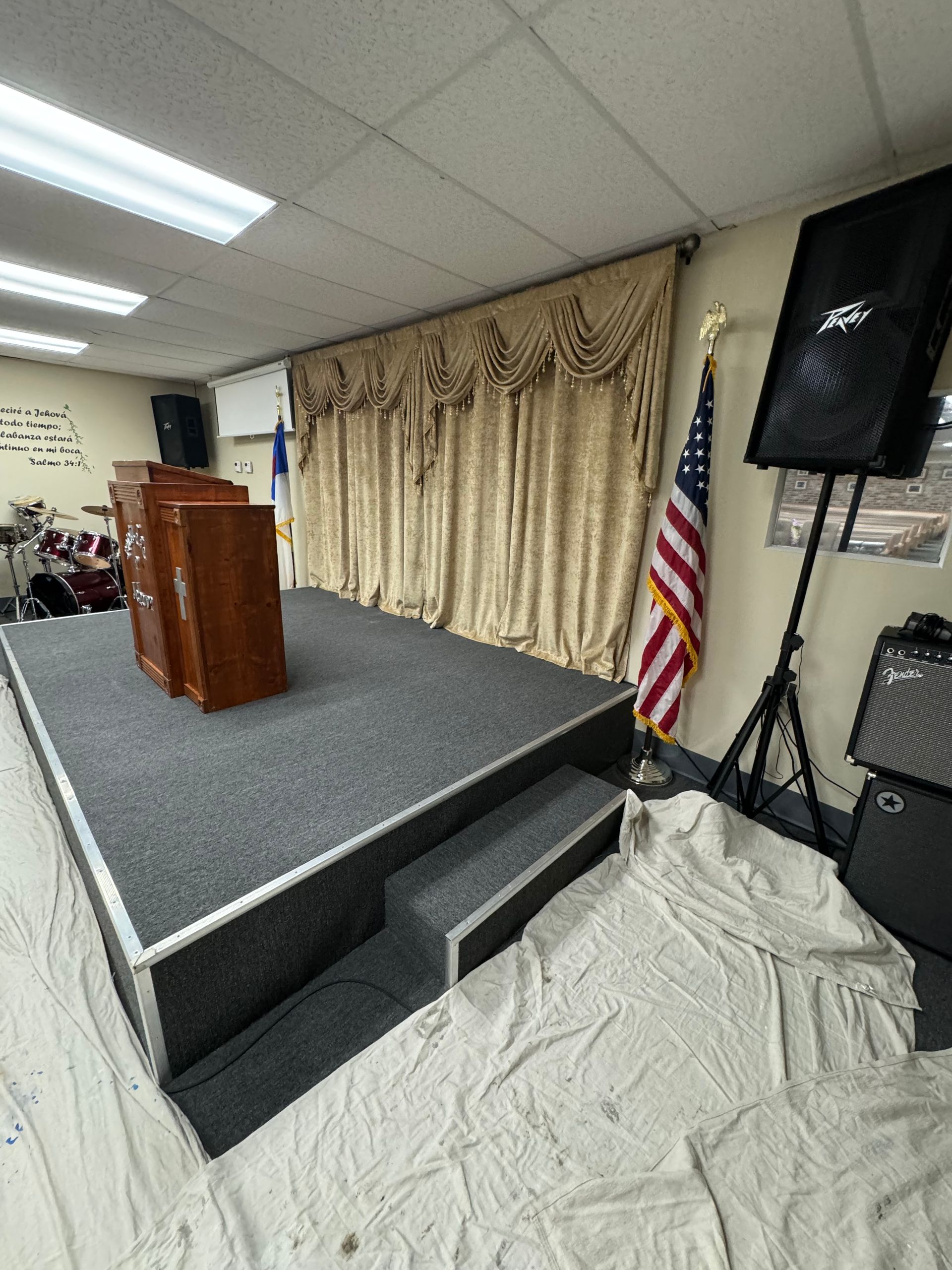 Stage with podium, curtains, American flag, speakers.