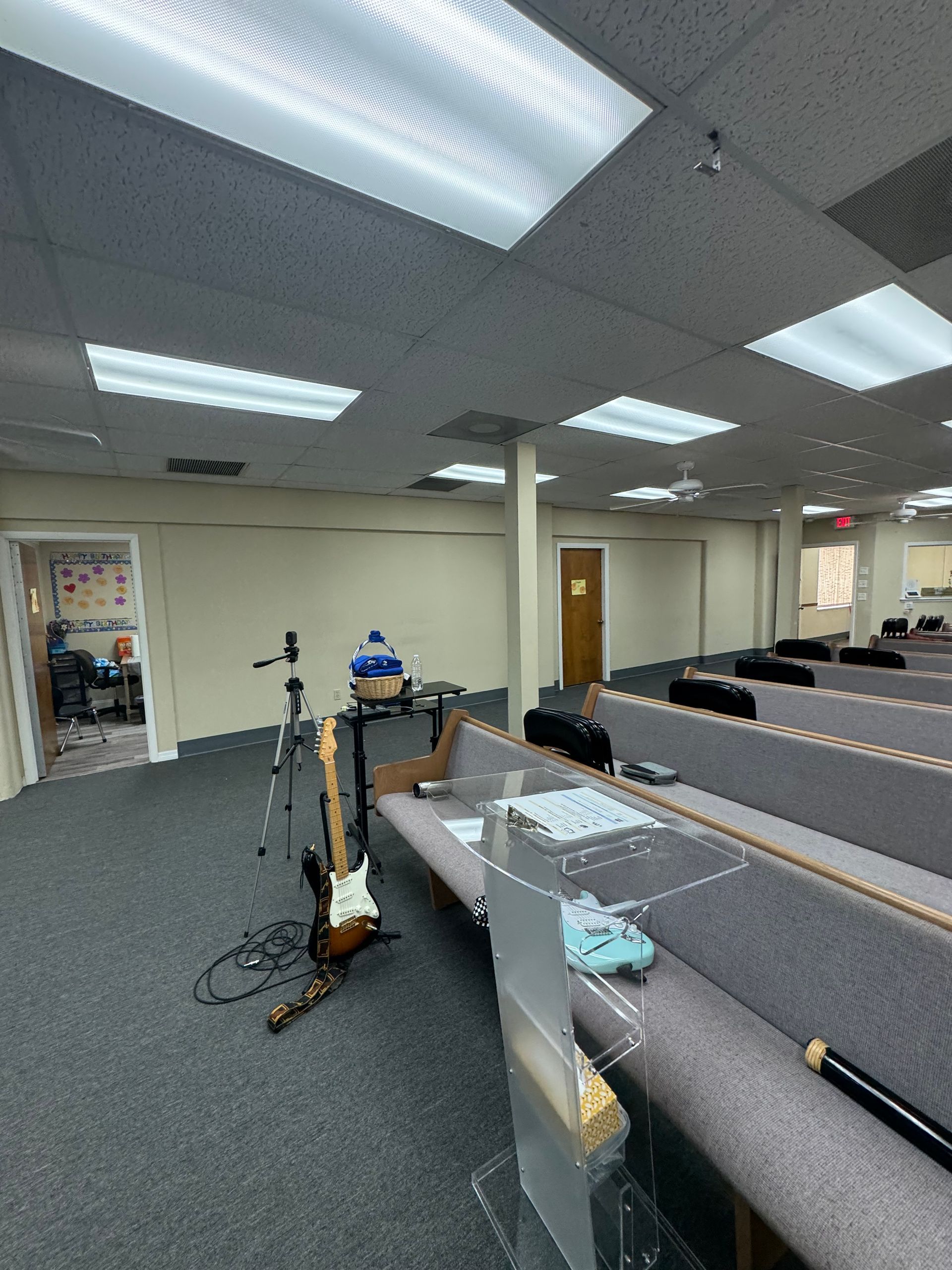 An empty church sanctuary with musical instruments set up in front of rows of pews.