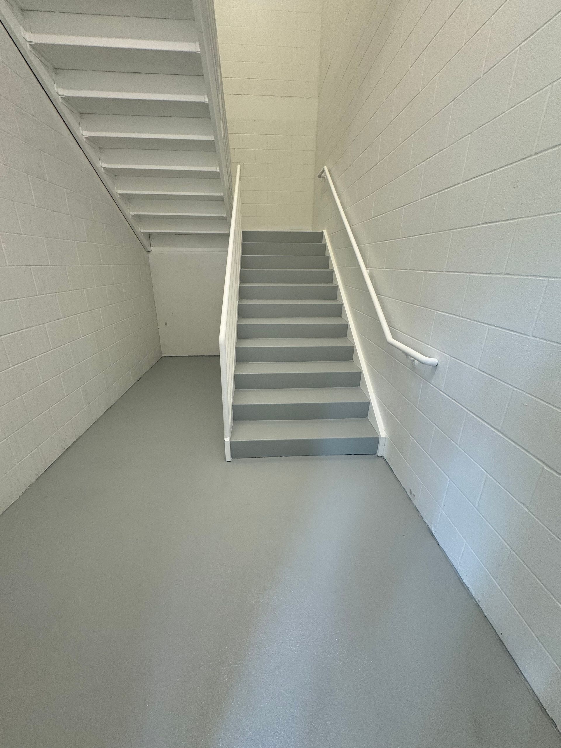 Indoor staircase painted white and gray. The walls are textured. The ground is gray.