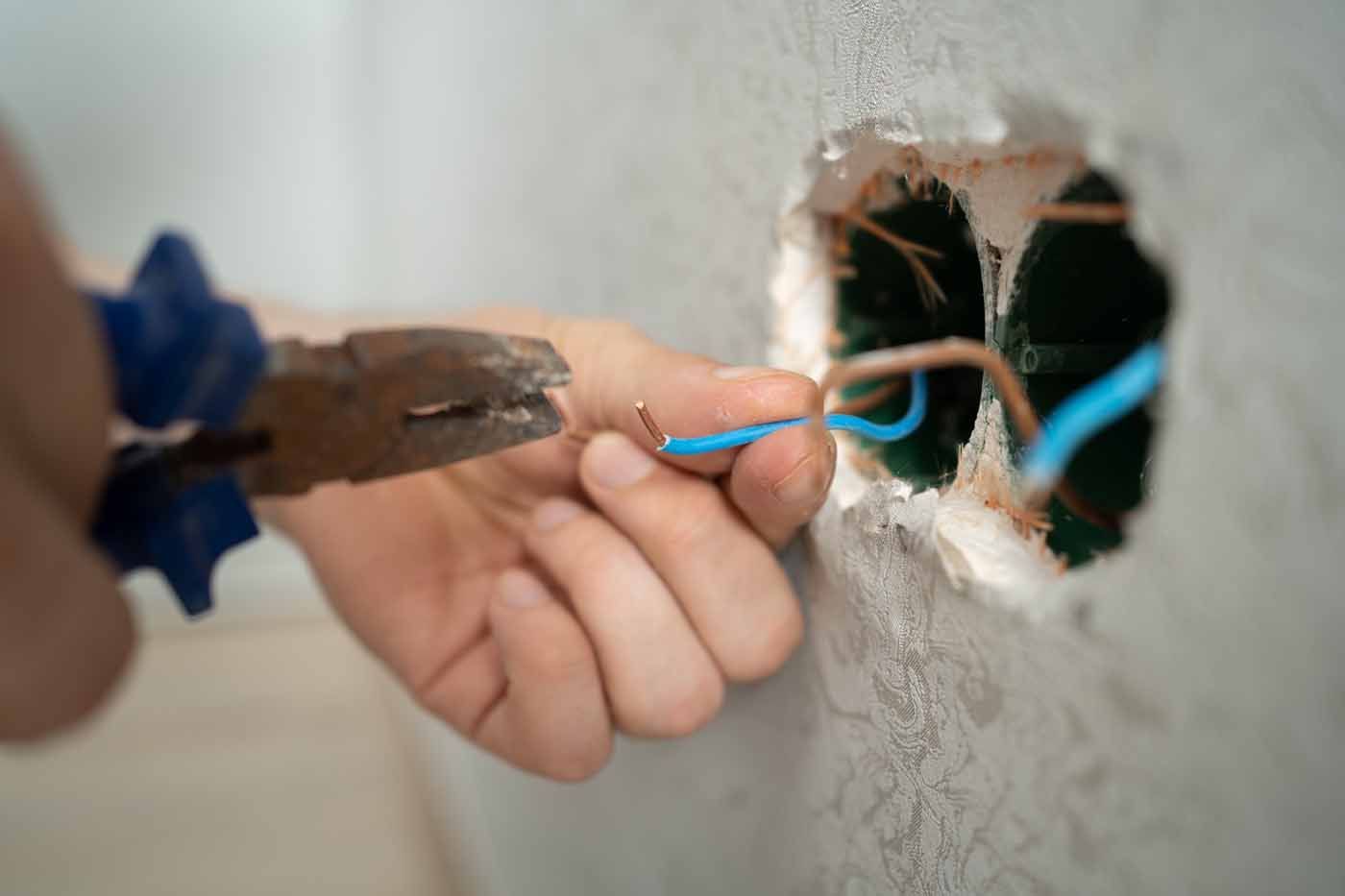 A person is cutting a wire with a pair of pliers.