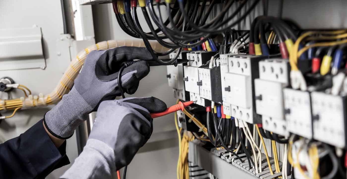 A person is working on an electrical panel with a screwdriver.