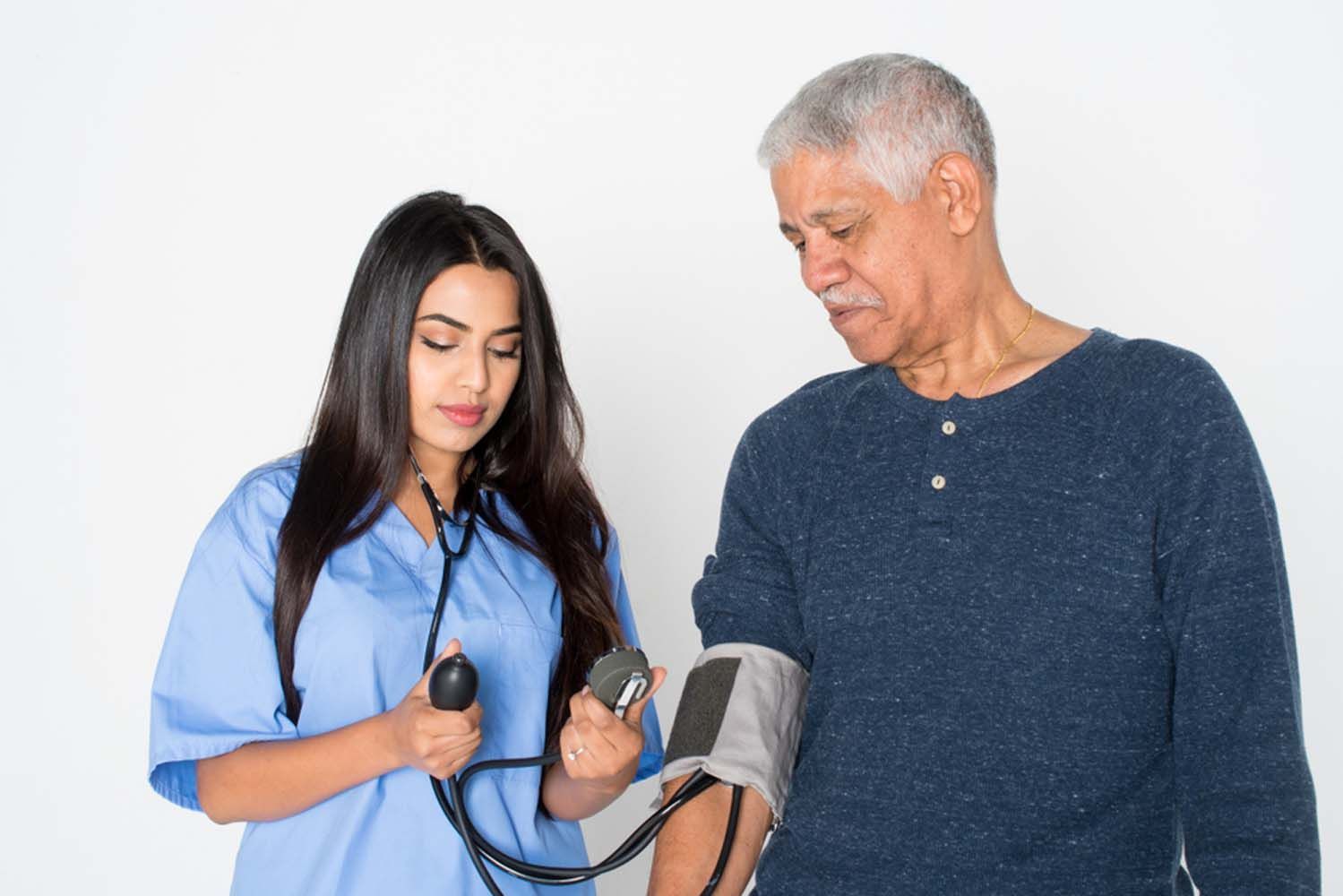 A nurse taking blood pressure on a old man