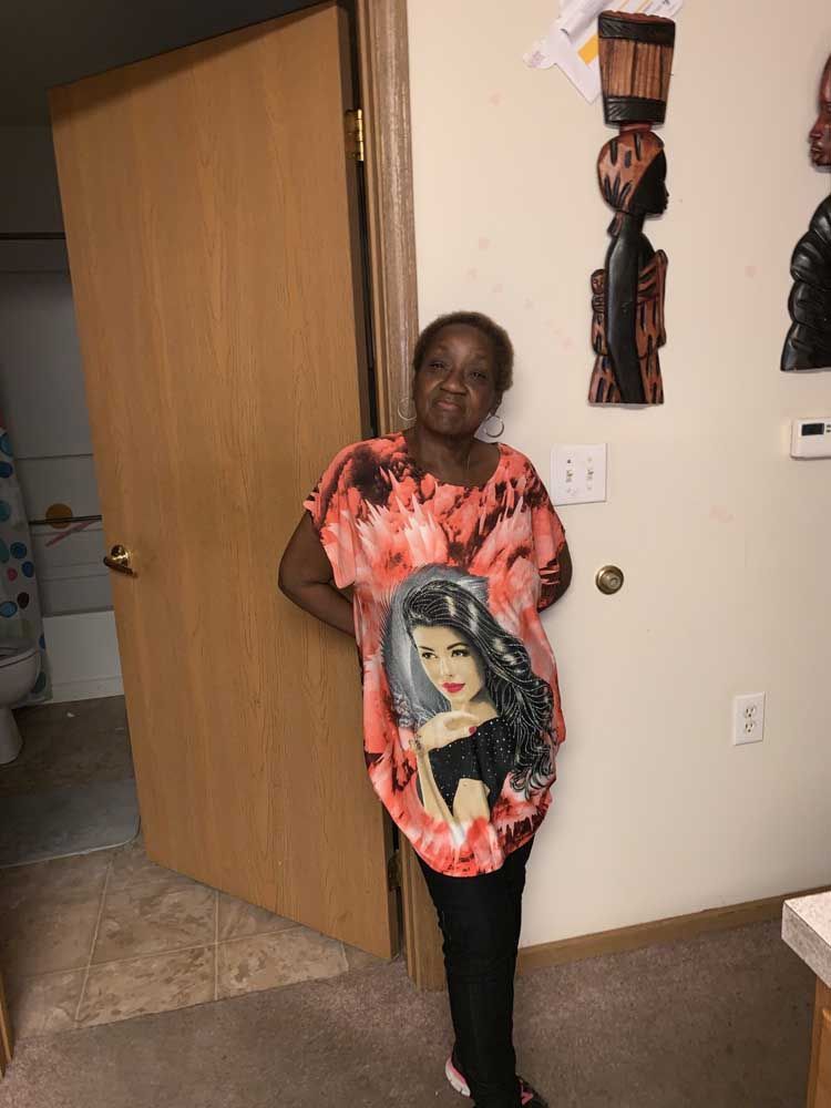 A woman is standing in a room wearing a shirt with a picture of a woman on it.