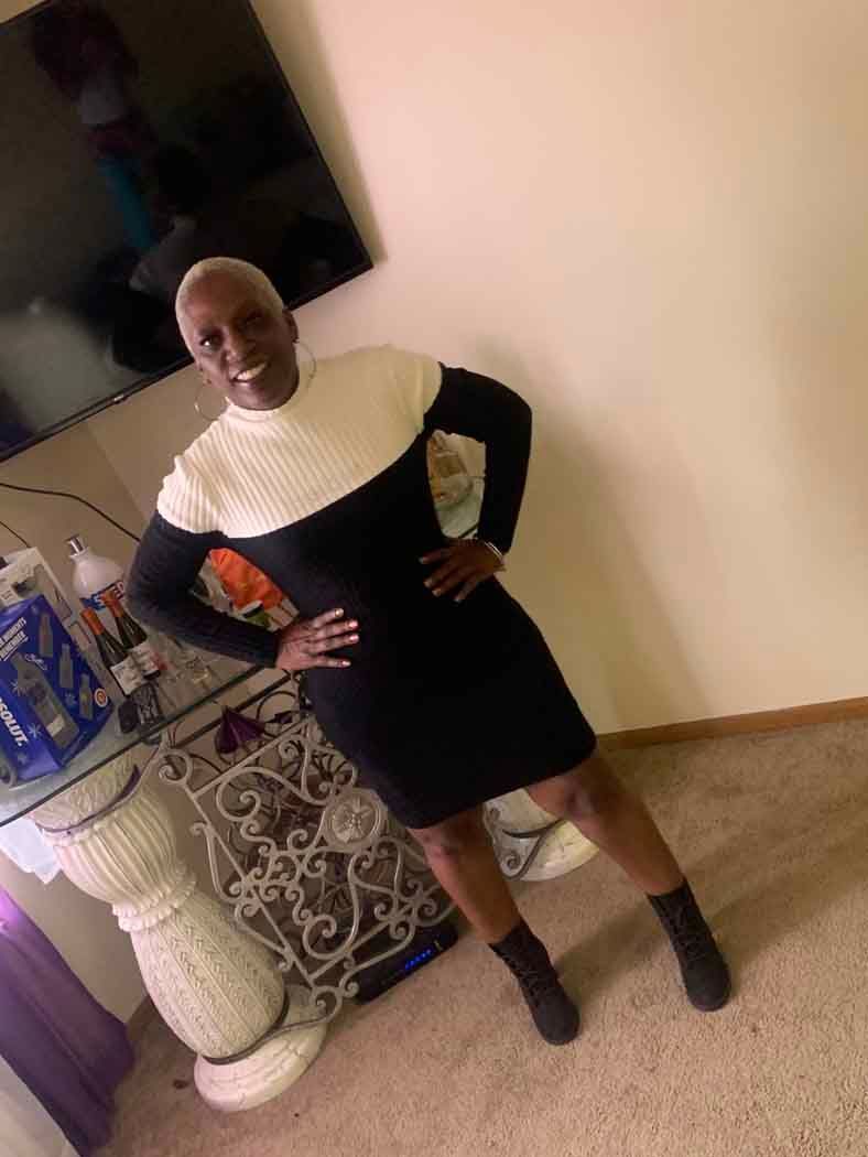 A woman in a black and white dress is standing in a living room.