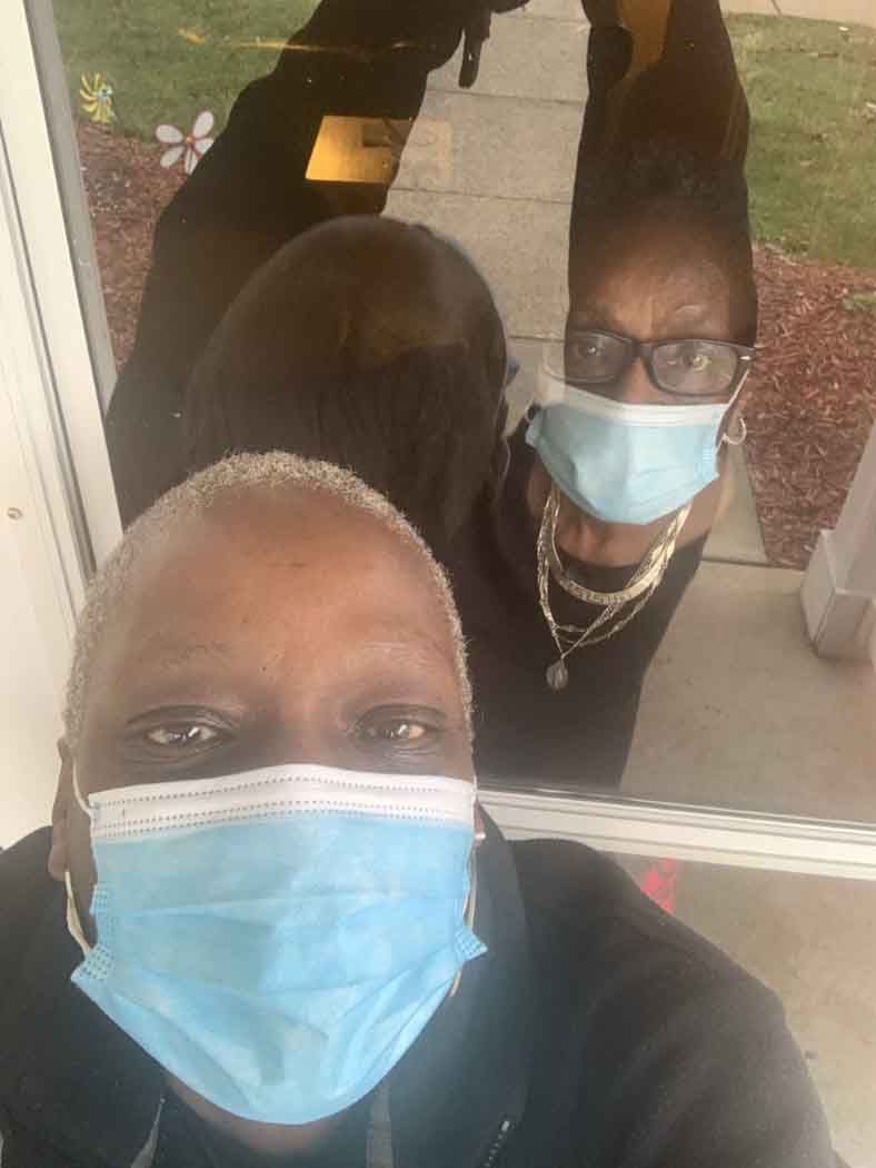 Two women wearing face masks and glasses are taking a selfie.