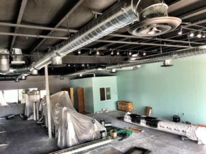 Interior view of a renovated commercial space, showing ductwork, exposed ceiling, and light-colored walls.