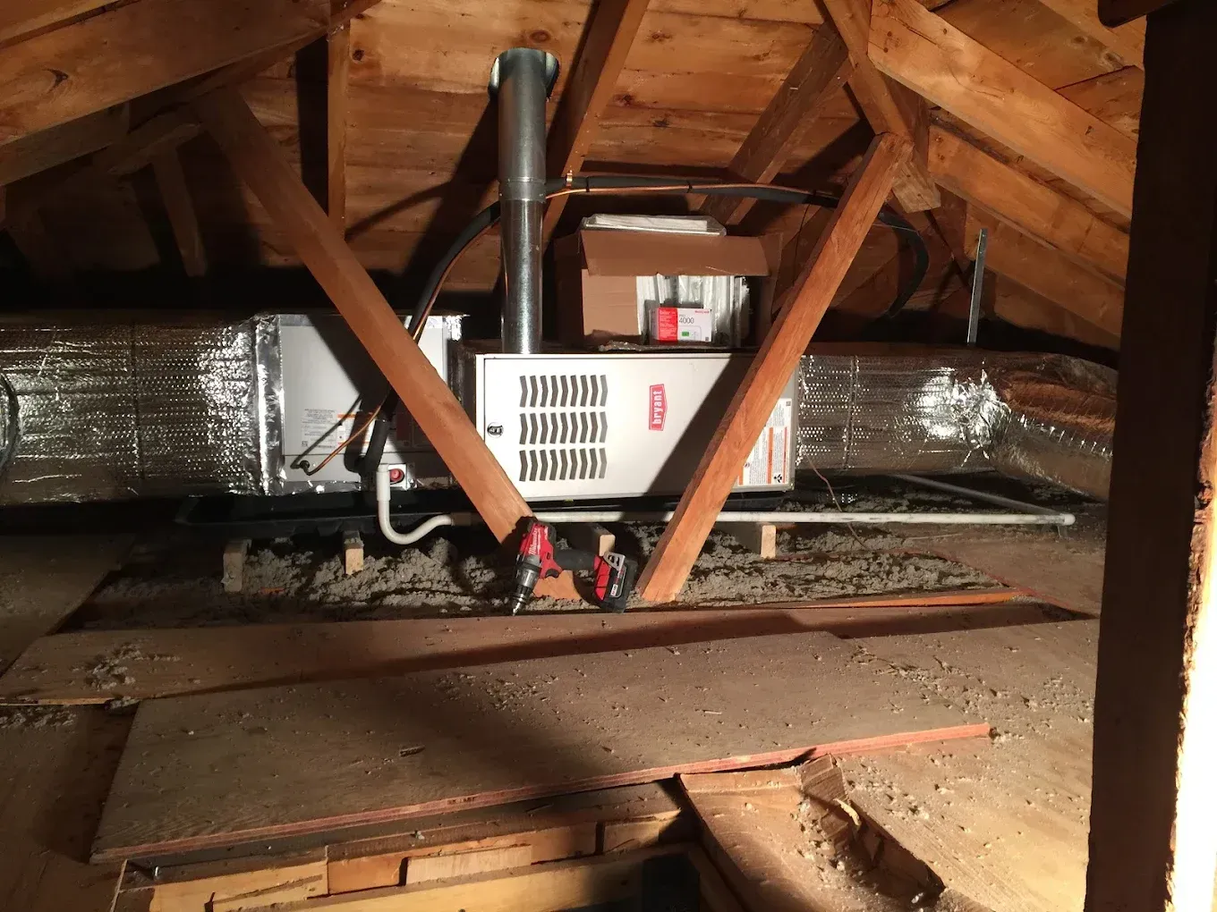 HVAC unit in an attic, surrounded by wooden beams and ductwork.