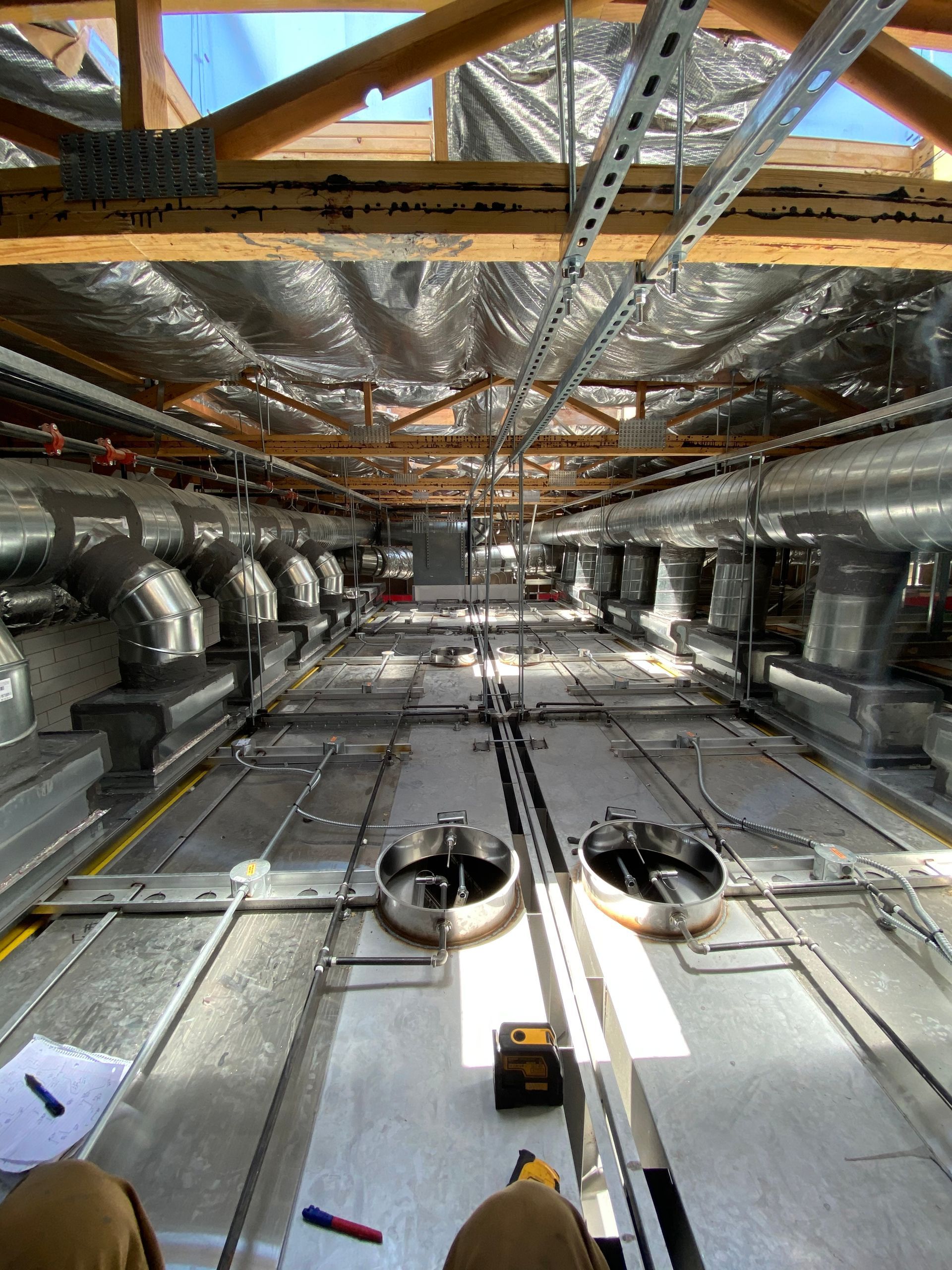 Interior view of a ceiling with ductwork, insulation, and circular vents installed.