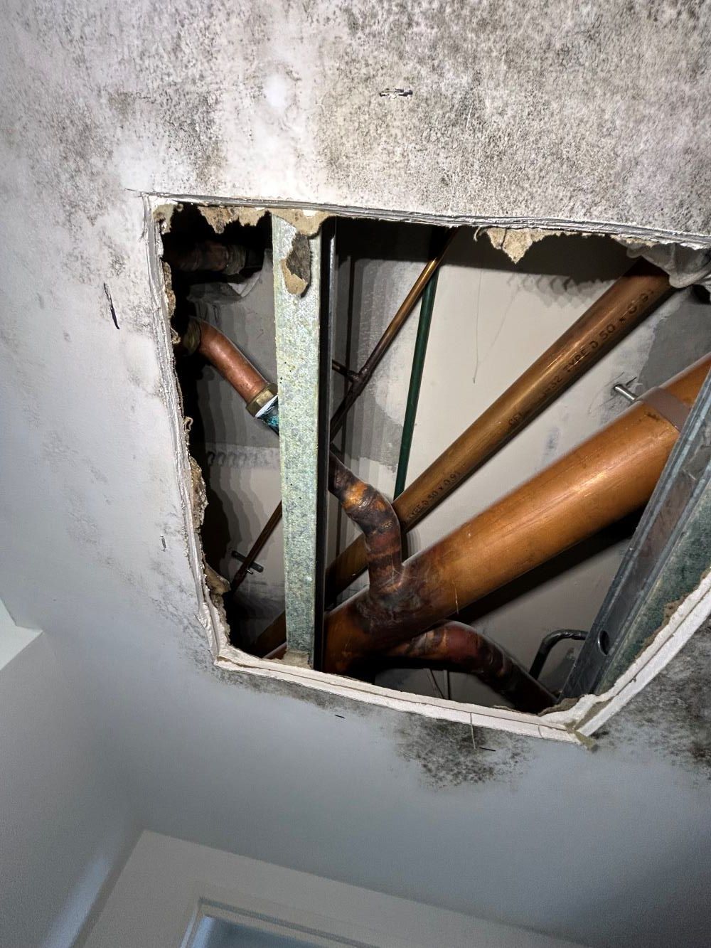 A Hole In The Ceiling With Copper Pipes Coming Out Of It — FNQ Maintenance Services In Parramatta Park, QLD
