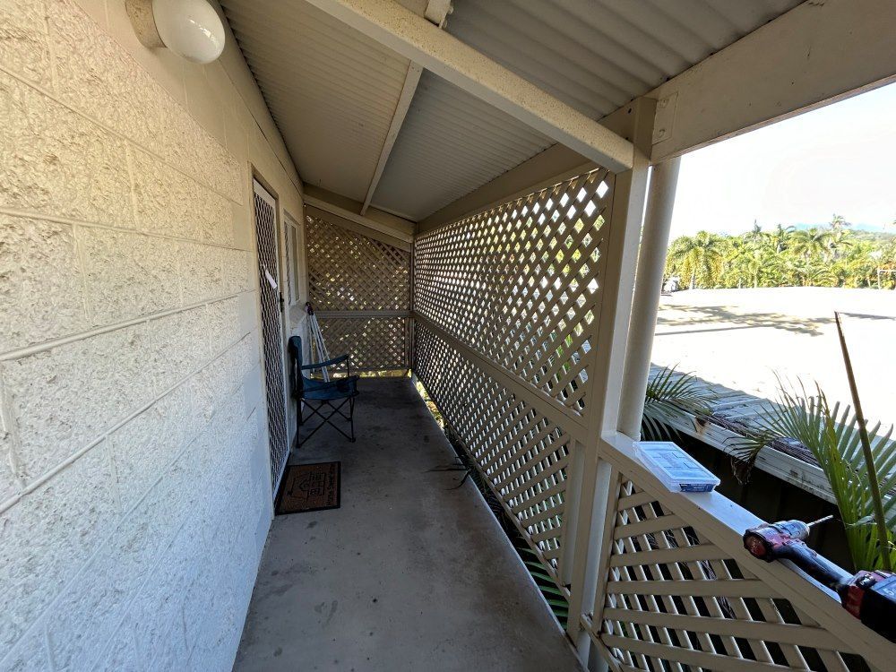 A Balcony With A Lattice Fence And A Chair On It — FNQ Maintenance Services In Parramatta Park, QLD
