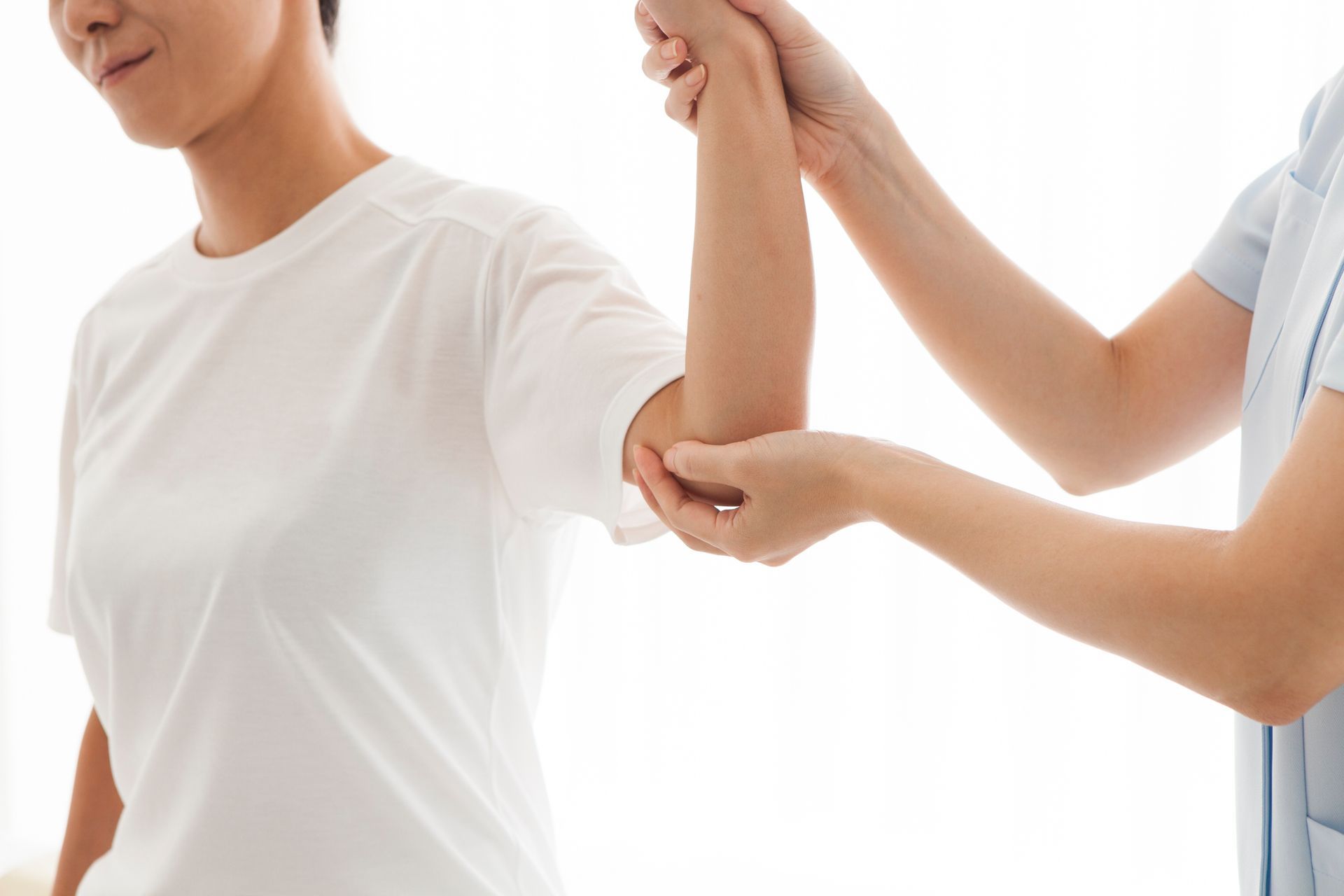 A person's arm is being examined by a medical professional, likely assessing range of motion. The setting appears to be a clinic or healthcare facility.