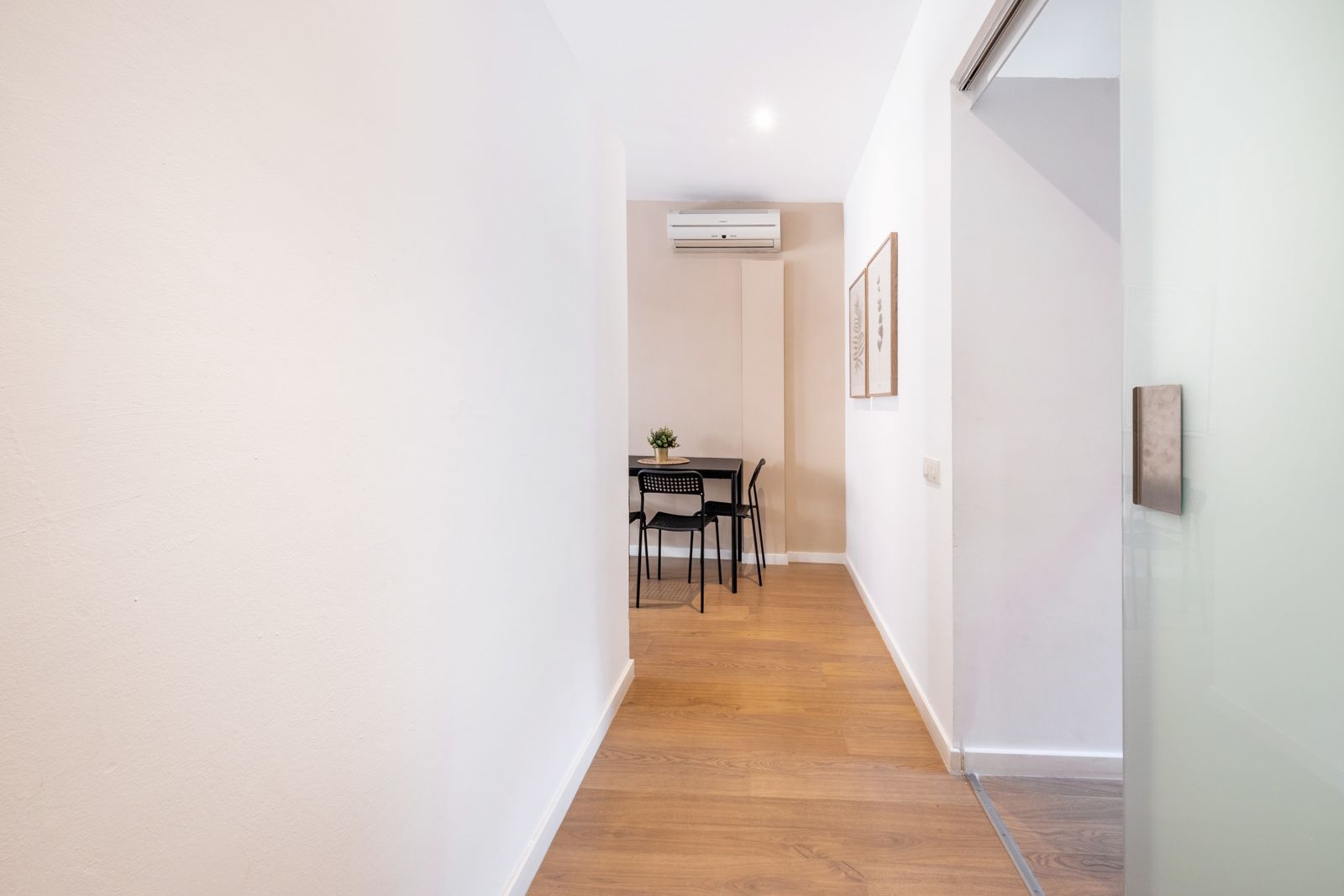 A long hallway leading to a dining room with a table and chairs.
