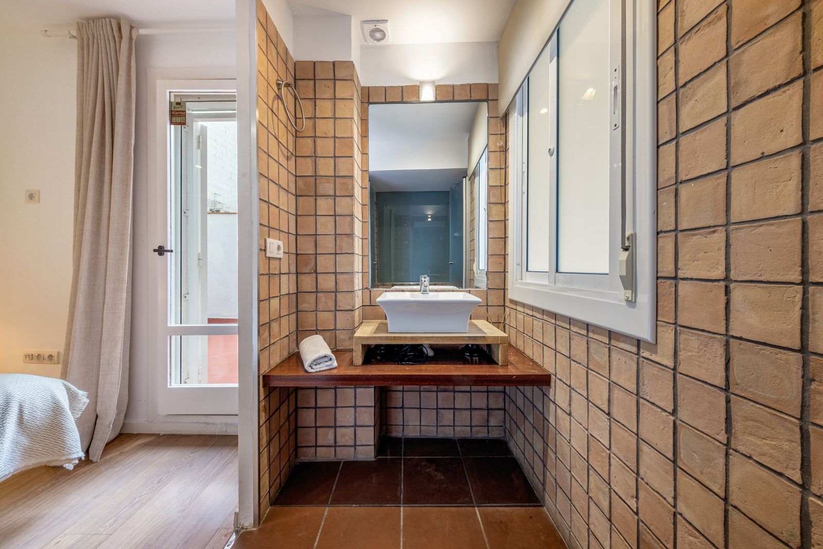 A bathroom with a sink , mirror and window.
