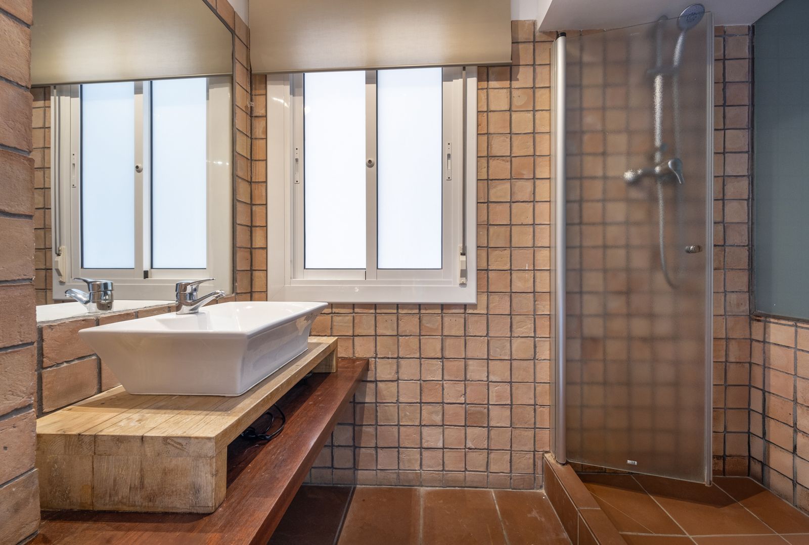 A bathroom with a sink , mirror and shower.
