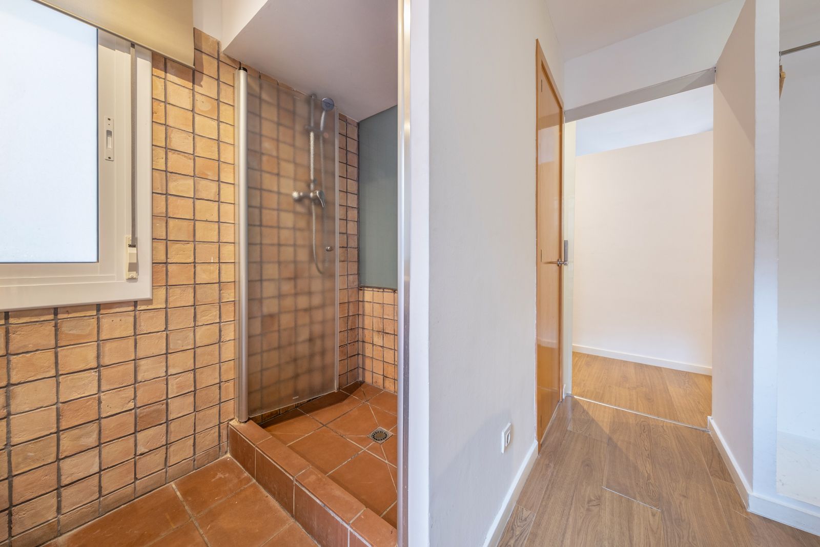 A bathroom with a walk in shower and a window.