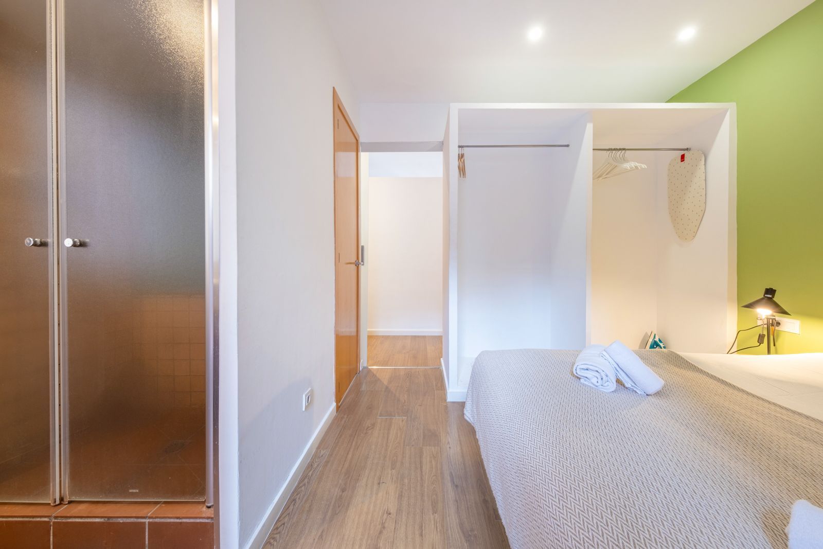 A bedroom with a bed and a walk in shower.