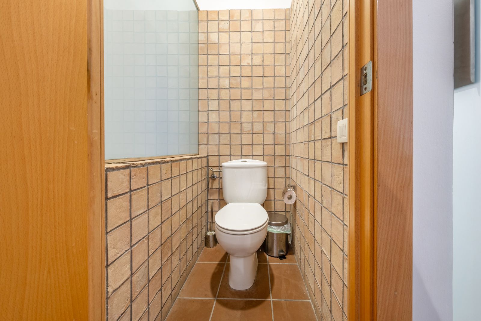 A toilet is sitting in a small bathroom next to a door.