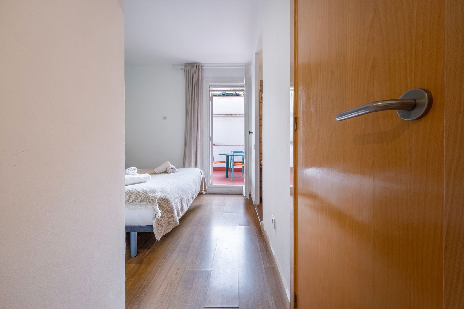 A bedroom with two beds and a door leading to a balcony.