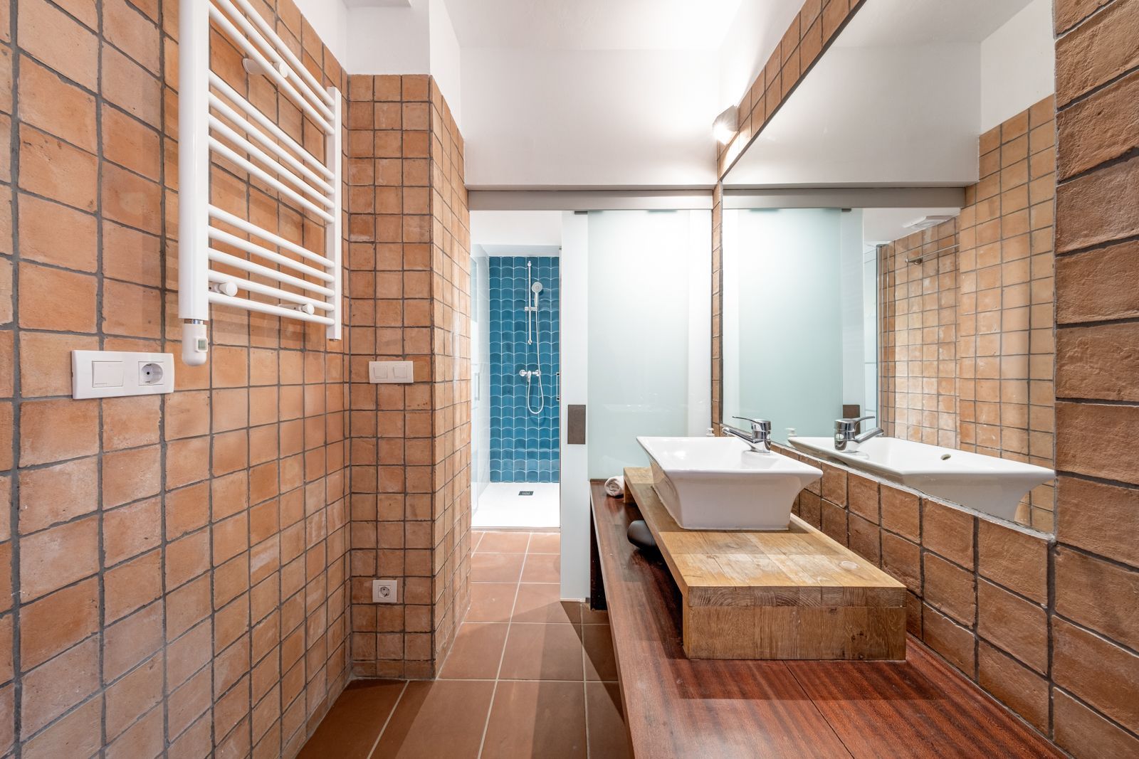 A bathroom with two sinks , a mirror and a towel rack.