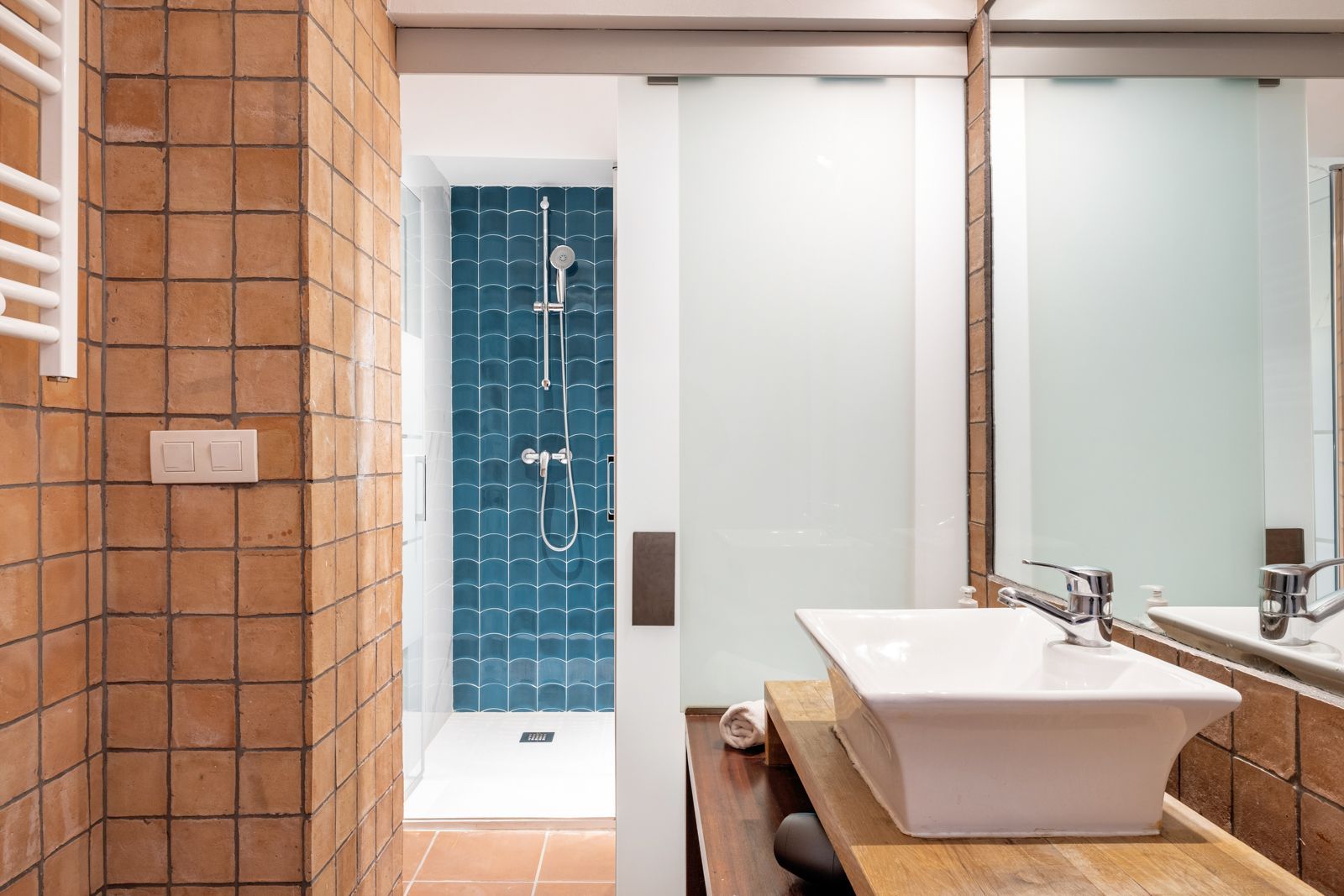 A bathroom with a sink , mirror and shower.
