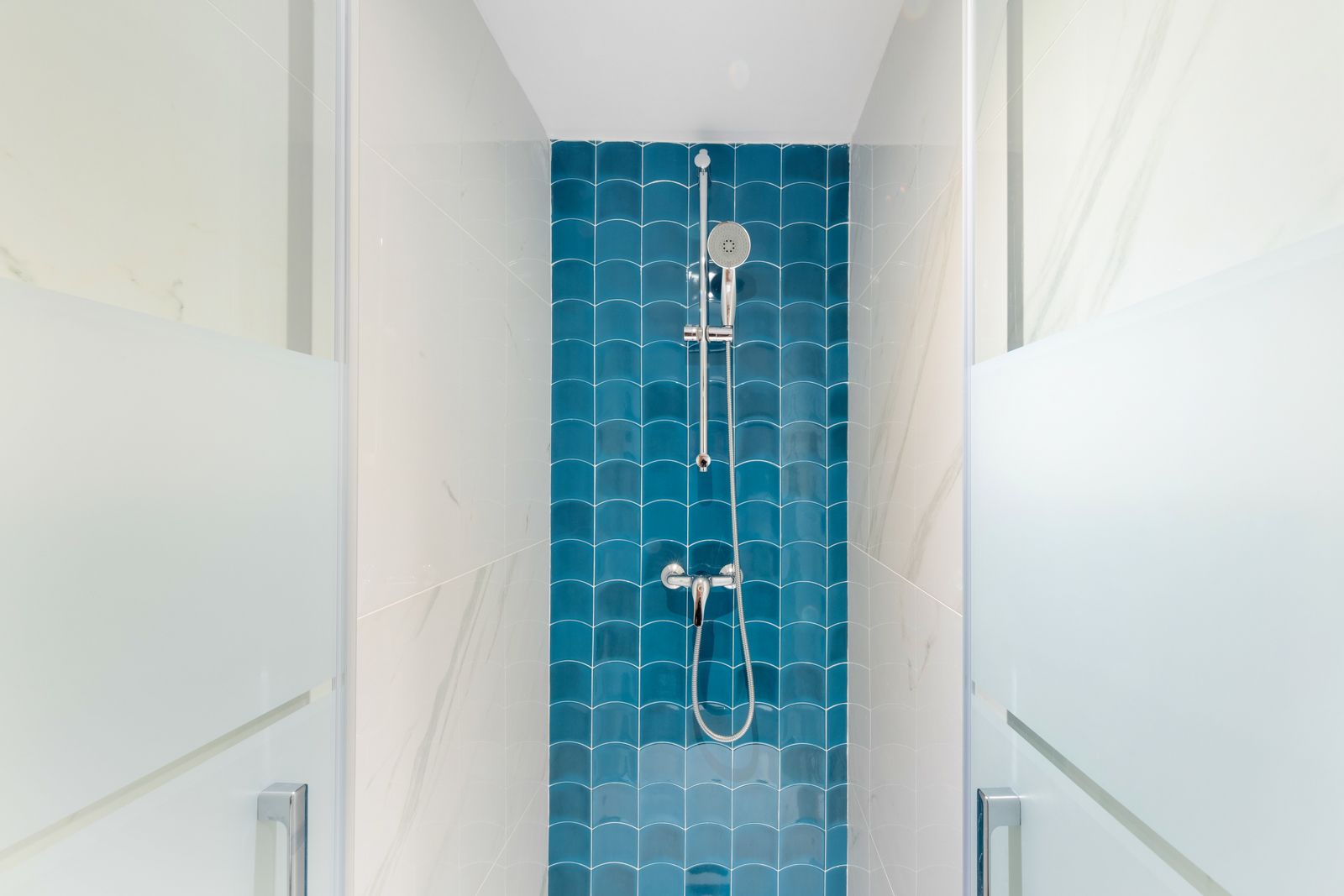 A shower stall with blue tiles and a shower head.