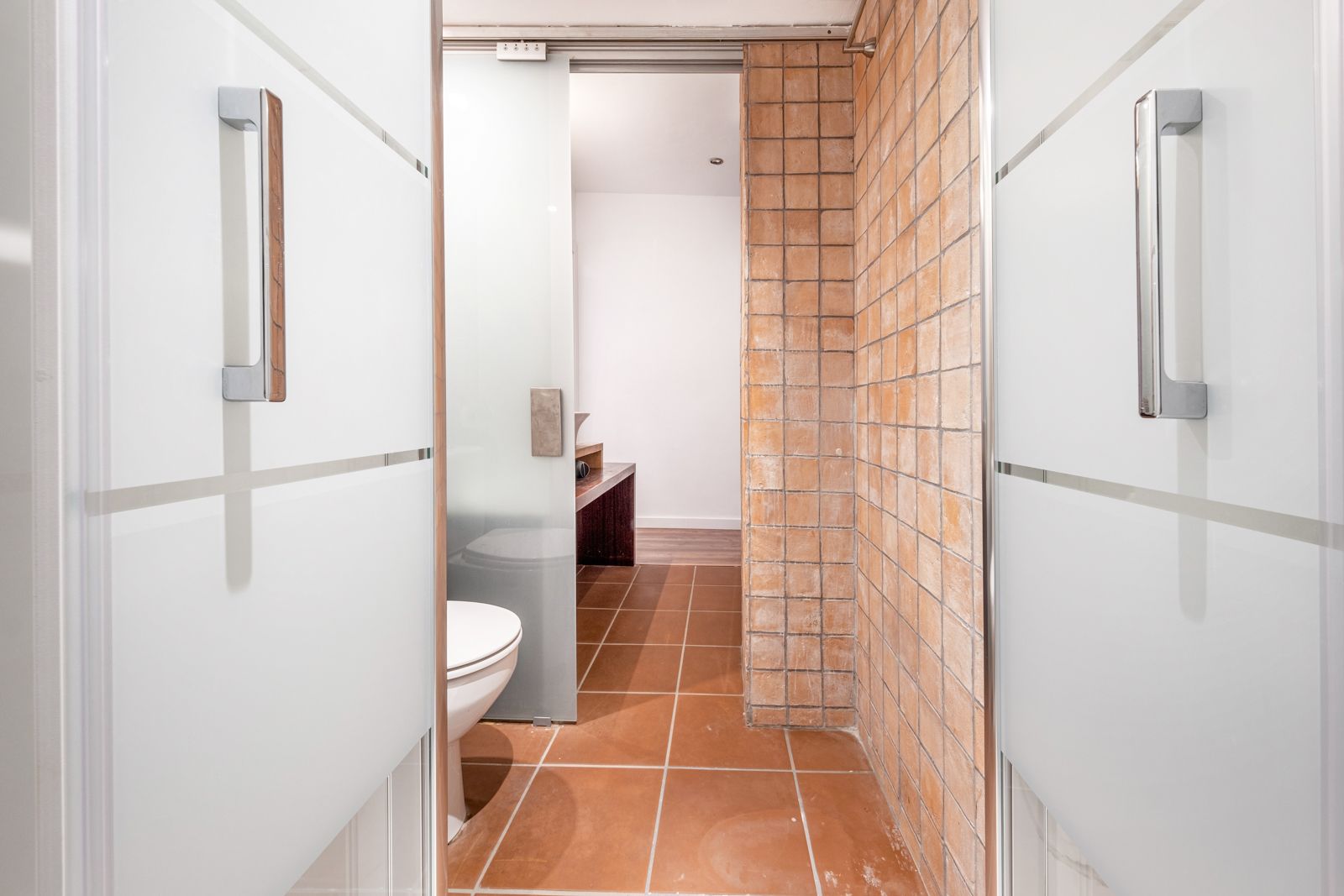 A bathroom with a toilet and a sliding glass door.