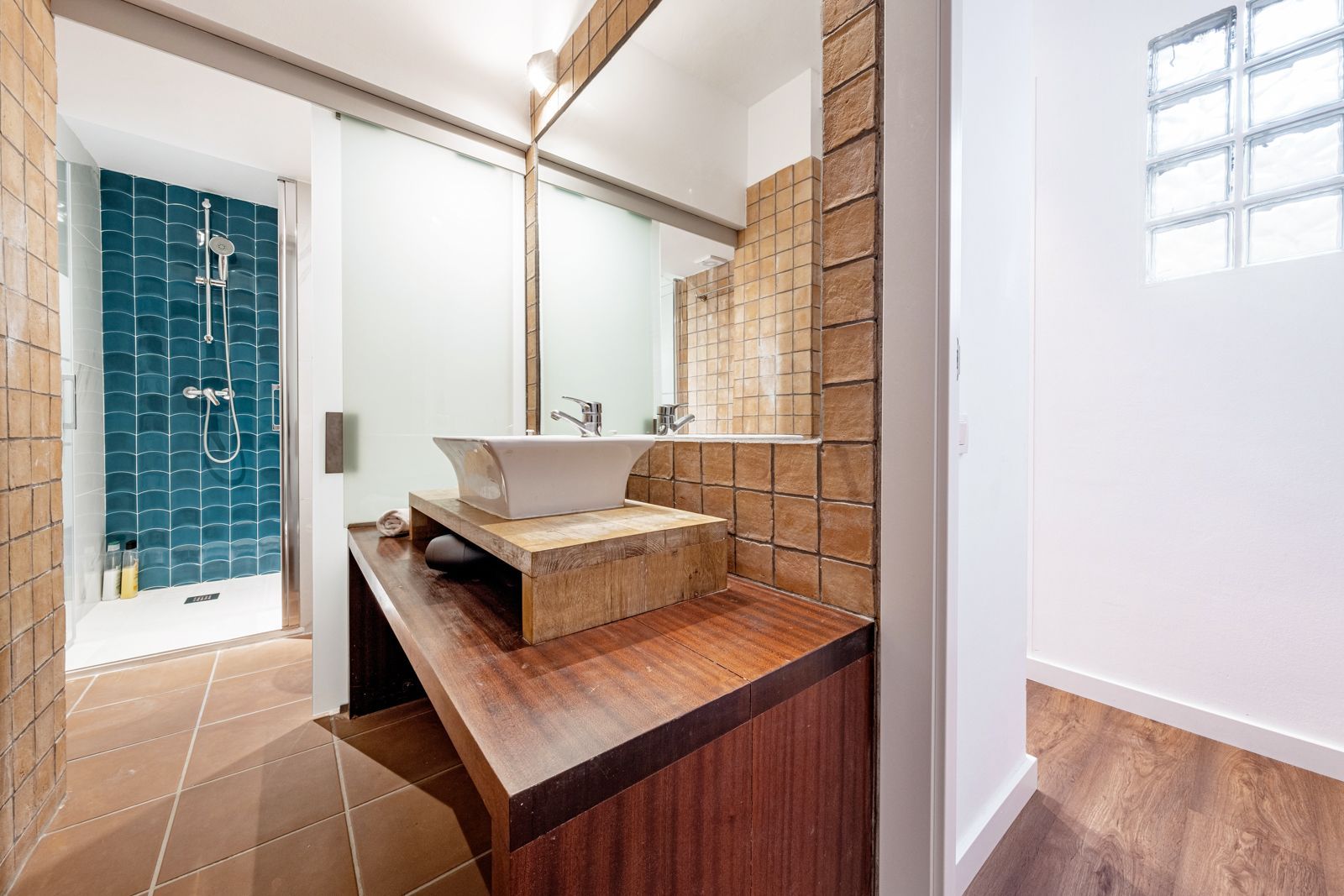 A bathroom with a sink , mirror and shower.