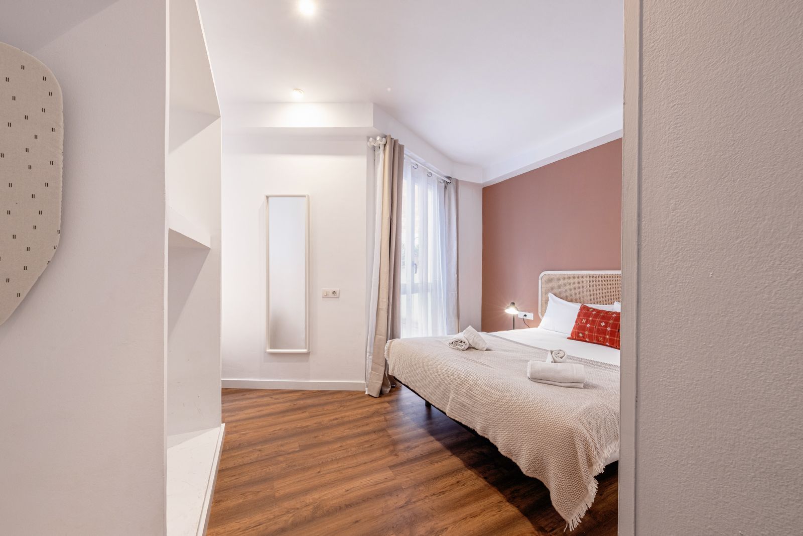 A bedroom with a large bed and a mirror on the wall.