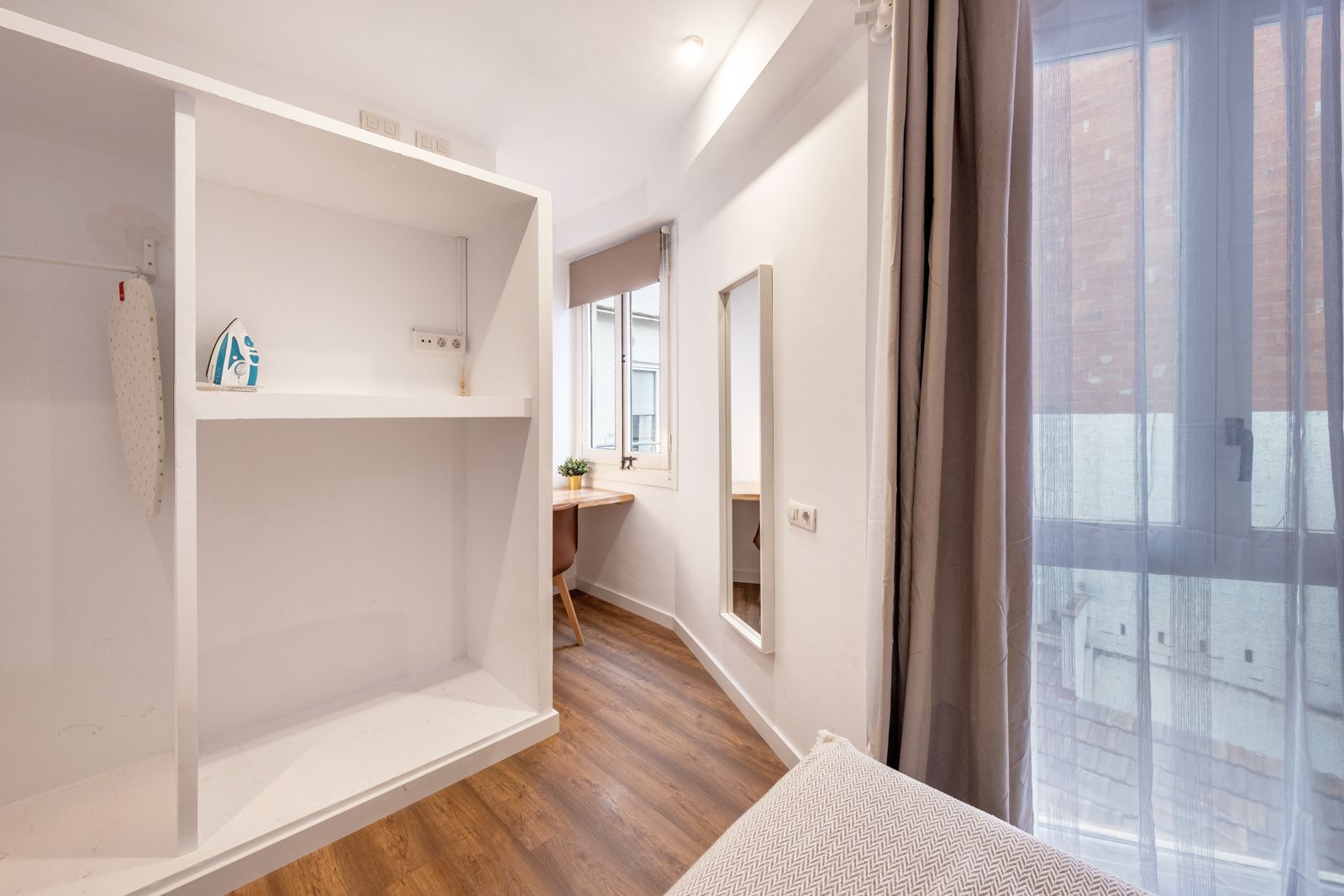 A bedroom with a bed , closet , mirror and window.