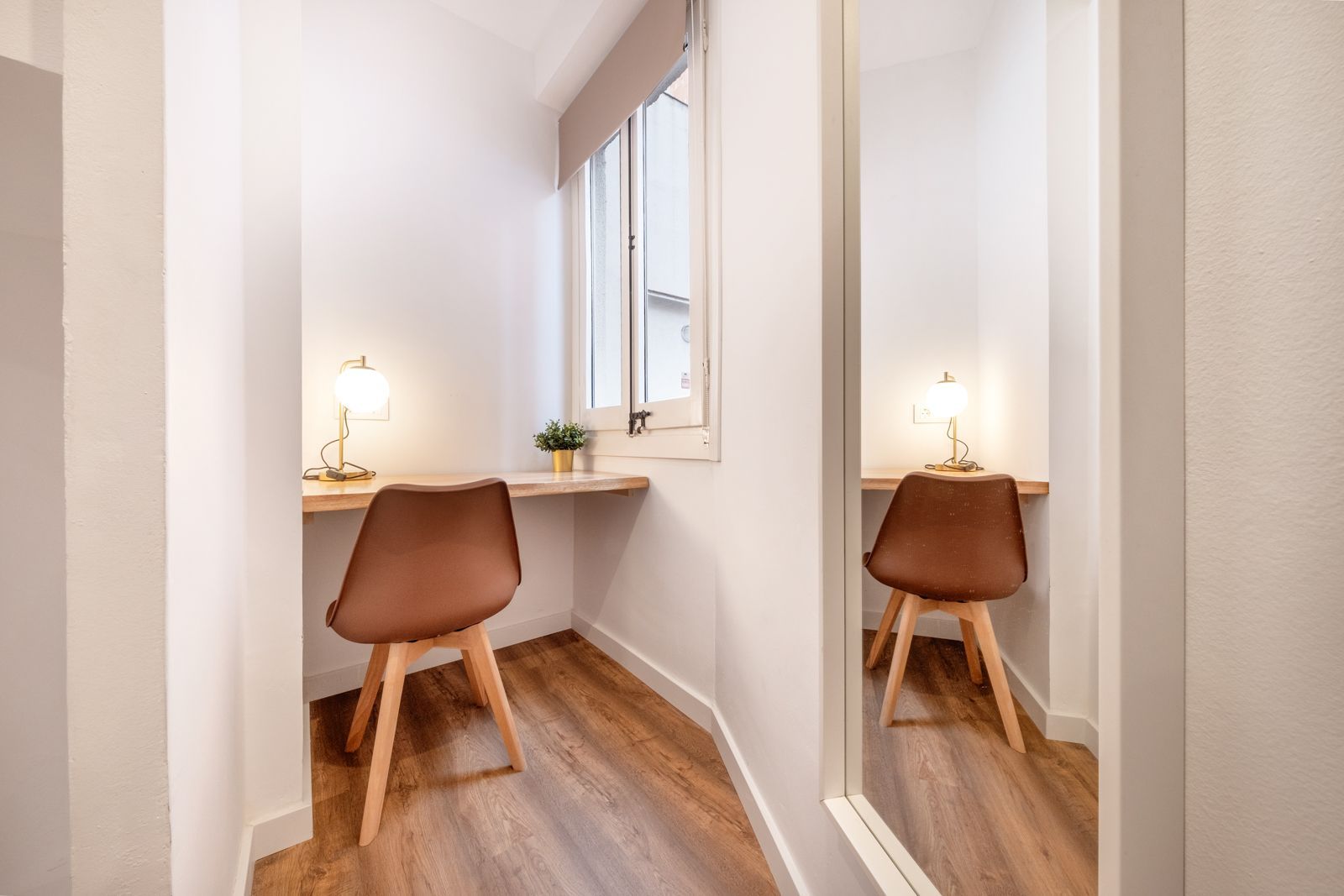 A small room with a desk and chairs and a mirror.