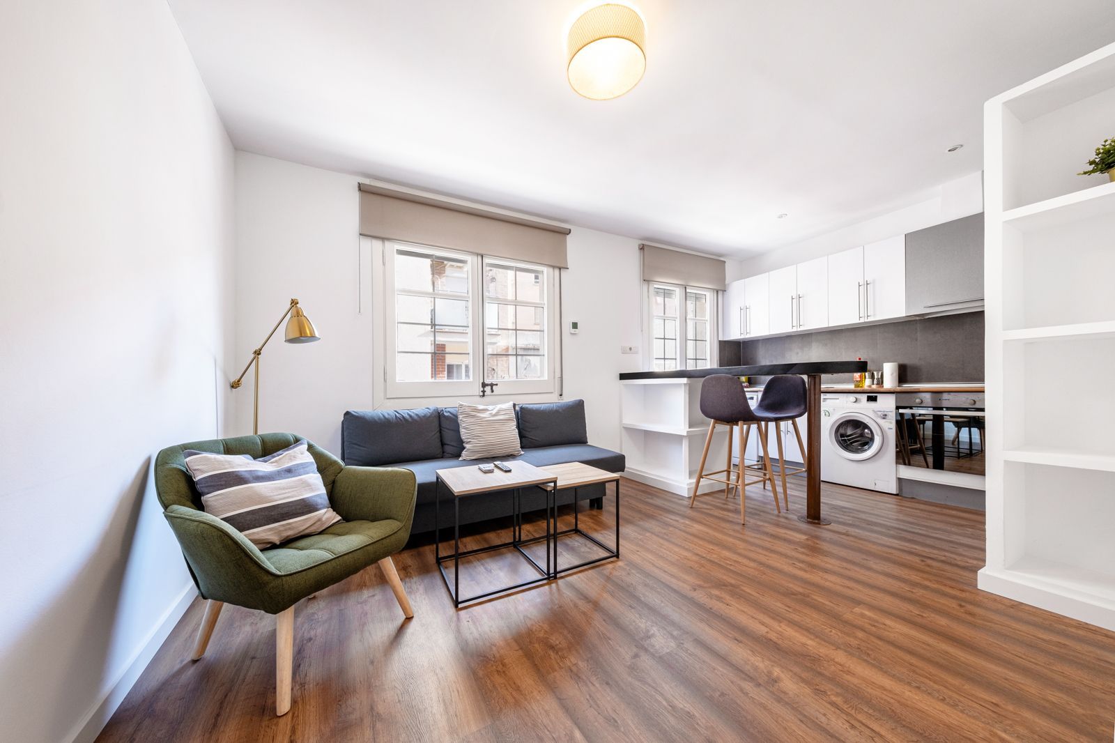 A living room with a couch , chair , coffee table and a washer and dryer.