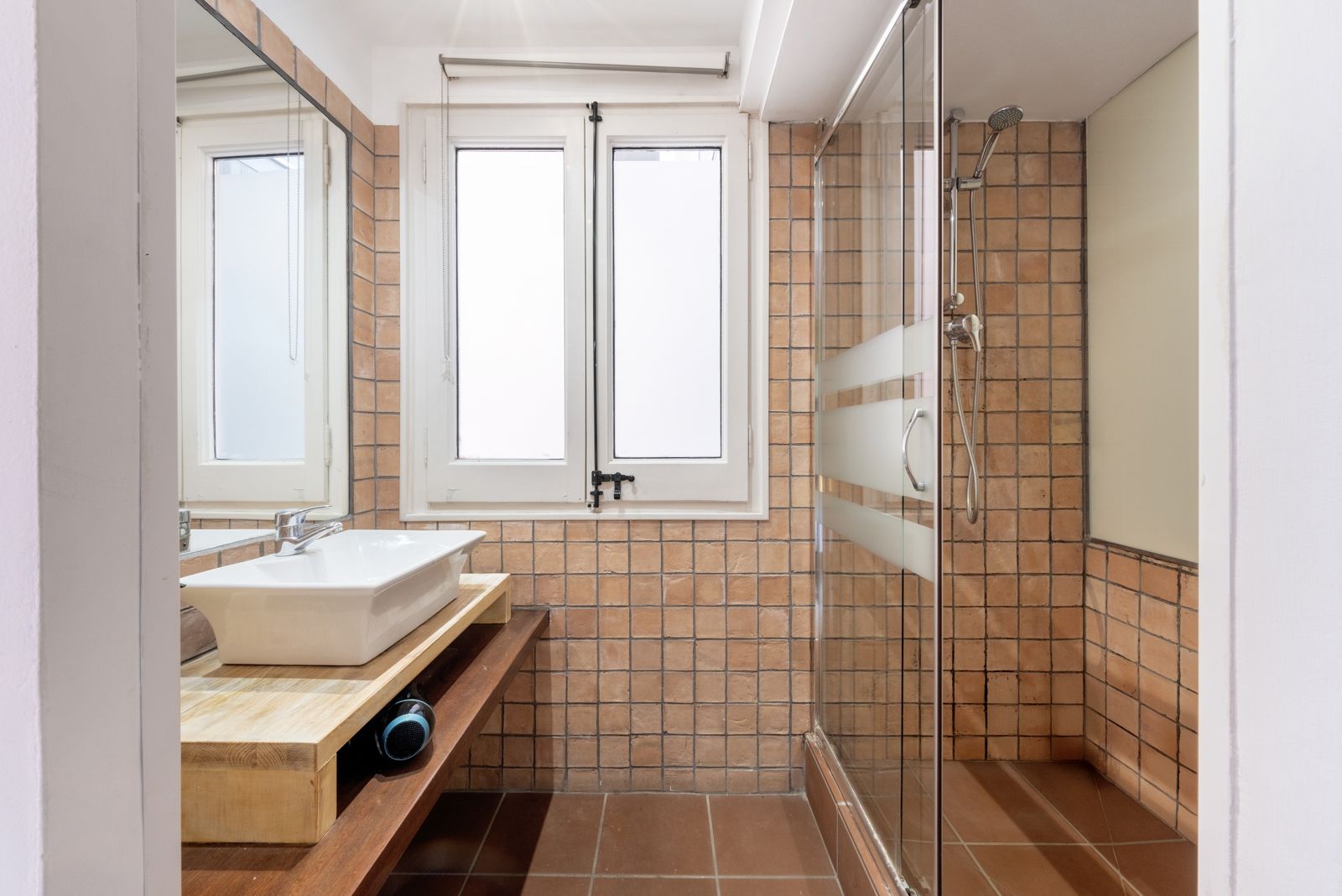 A bathroom with a sink , mirror and walk in shower.