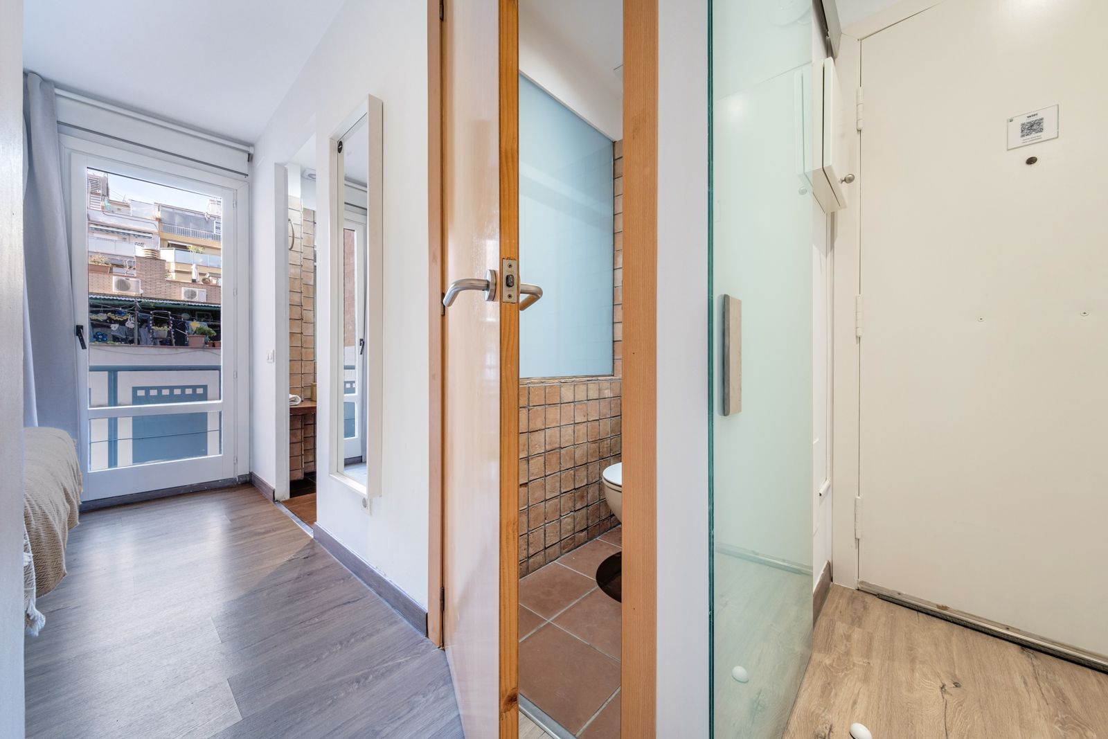 A hallway with a glass door leading to a bathroom.